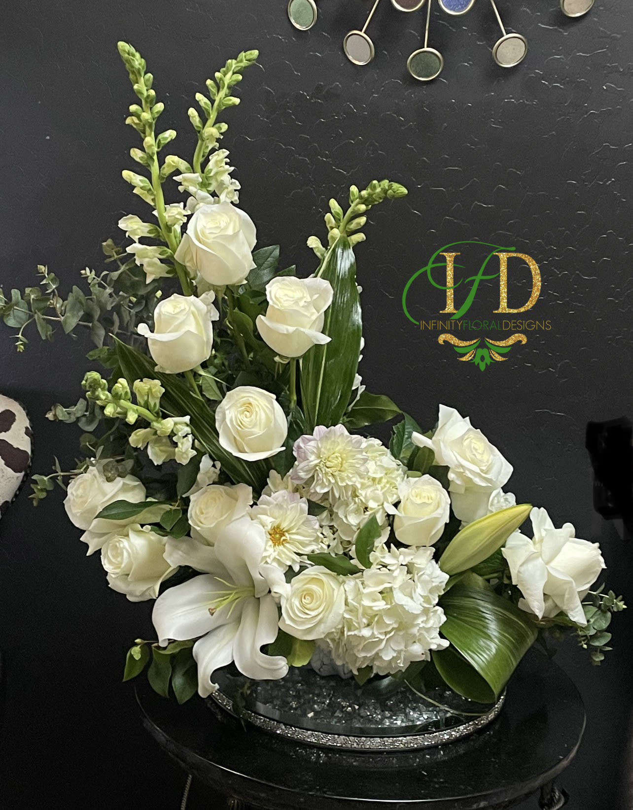 White roses and lilies arranged in a low oval centerpiece