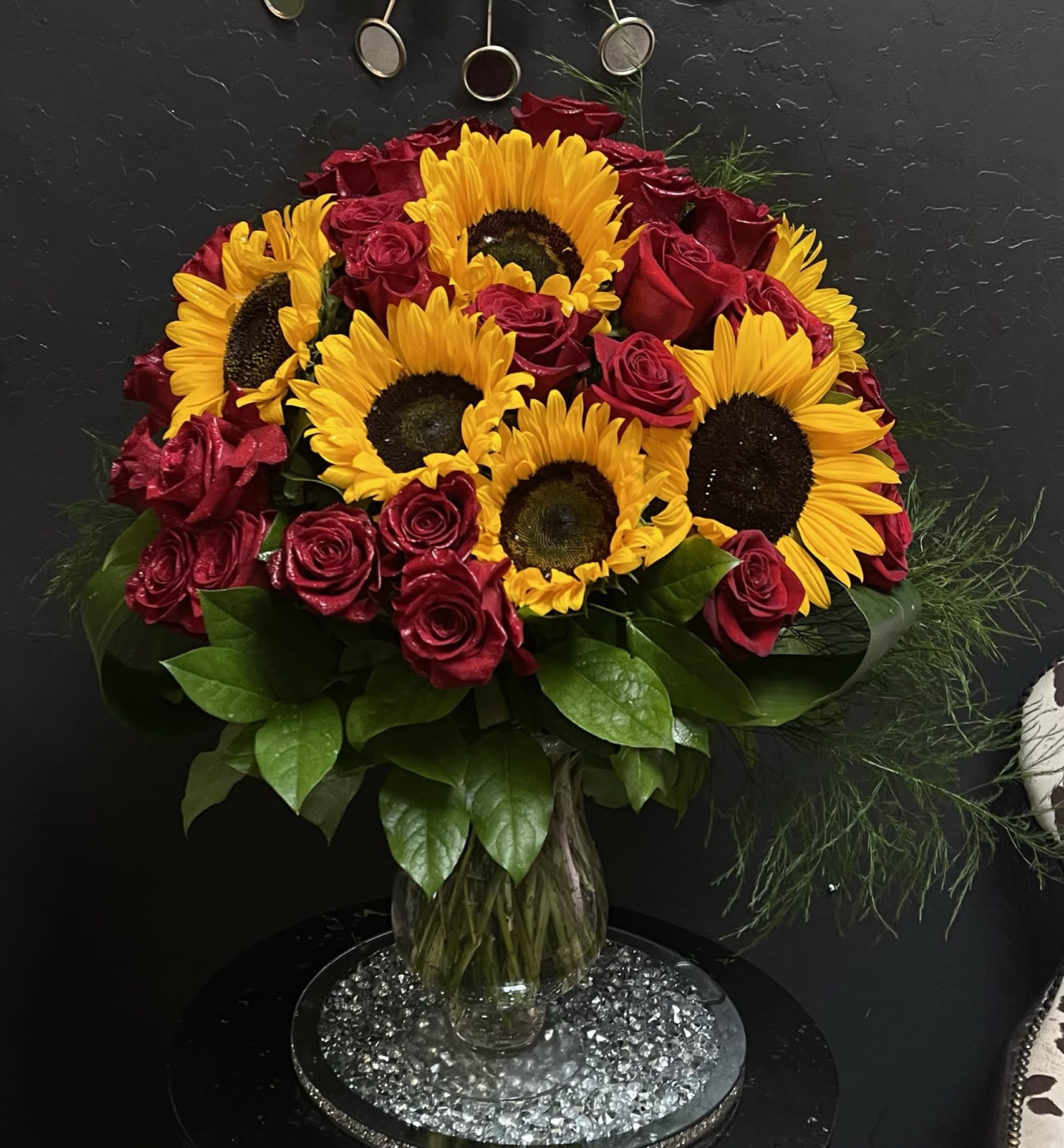 Bouquet of red roses and yellow sunflowers in a clear glass vase