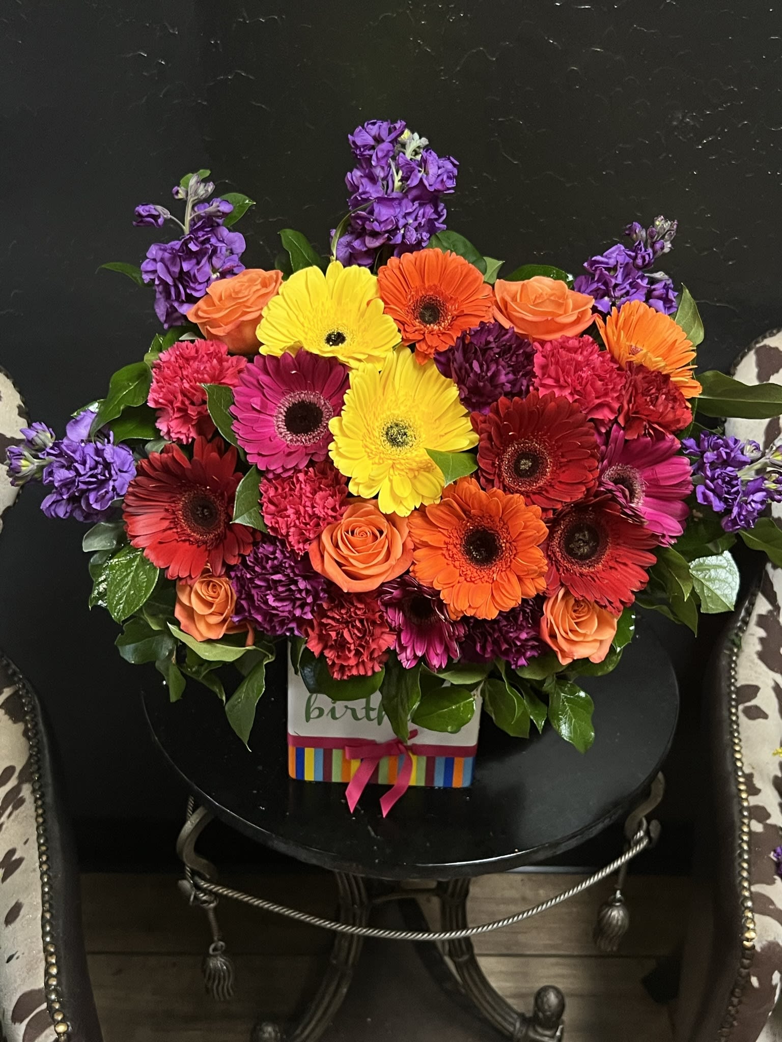 Bright mixed bouquet with gerbera daisies, roses, and purple blooms in a gift box