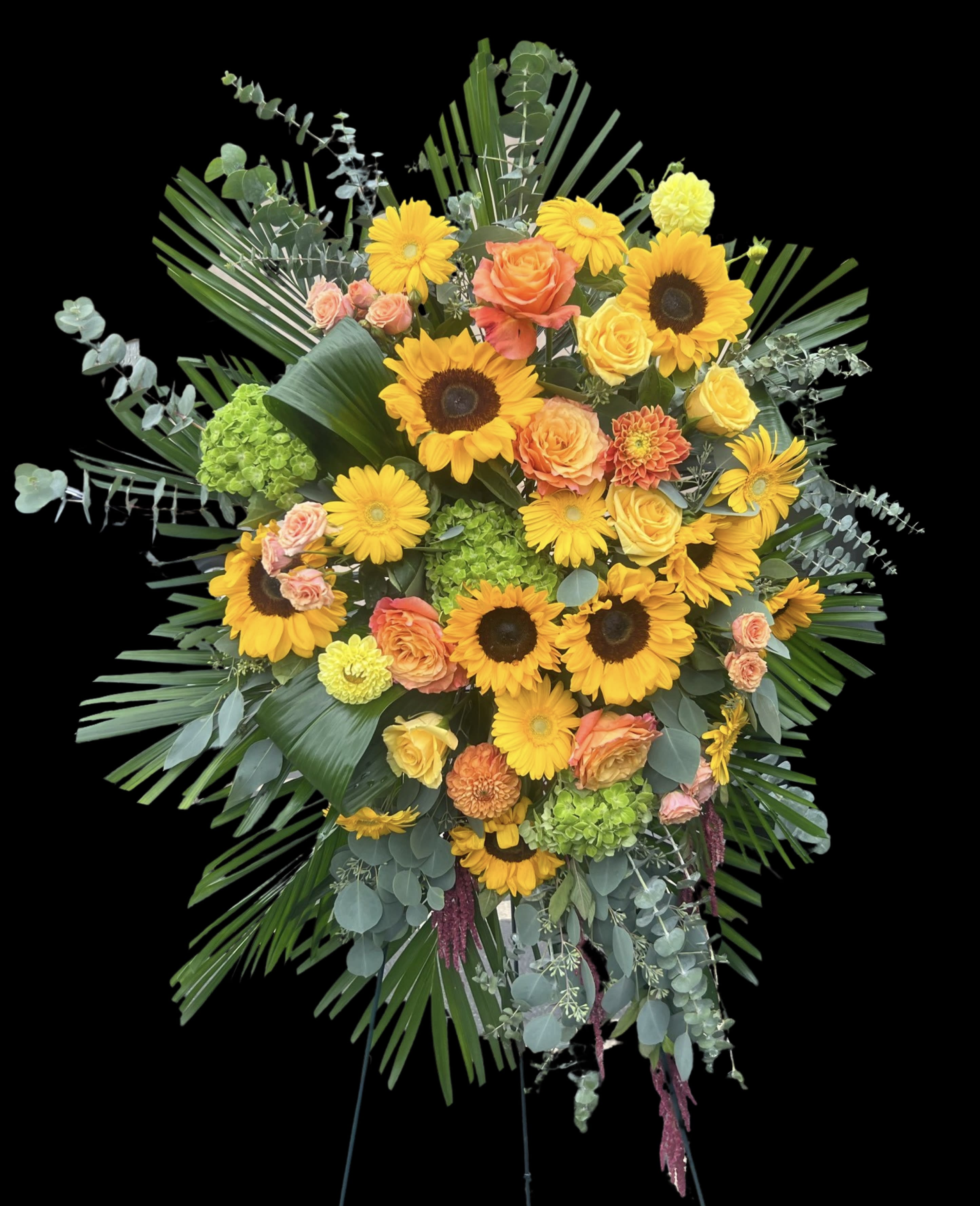 Large standing floral spray with sunflowers, roses, and greenery on an easel