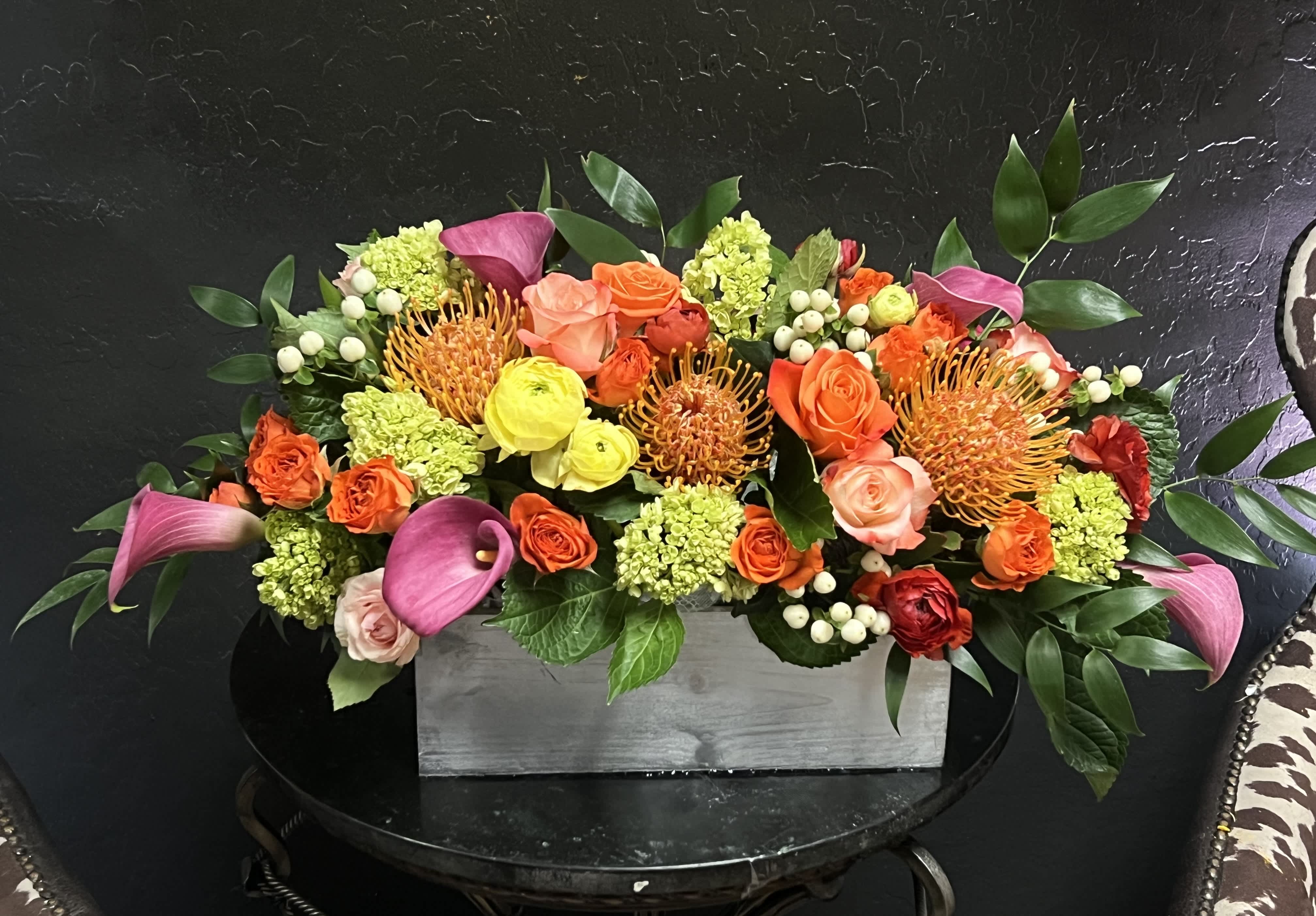 Colorful floral arrangement in a gray rectangular box with pink calla lilies and roses