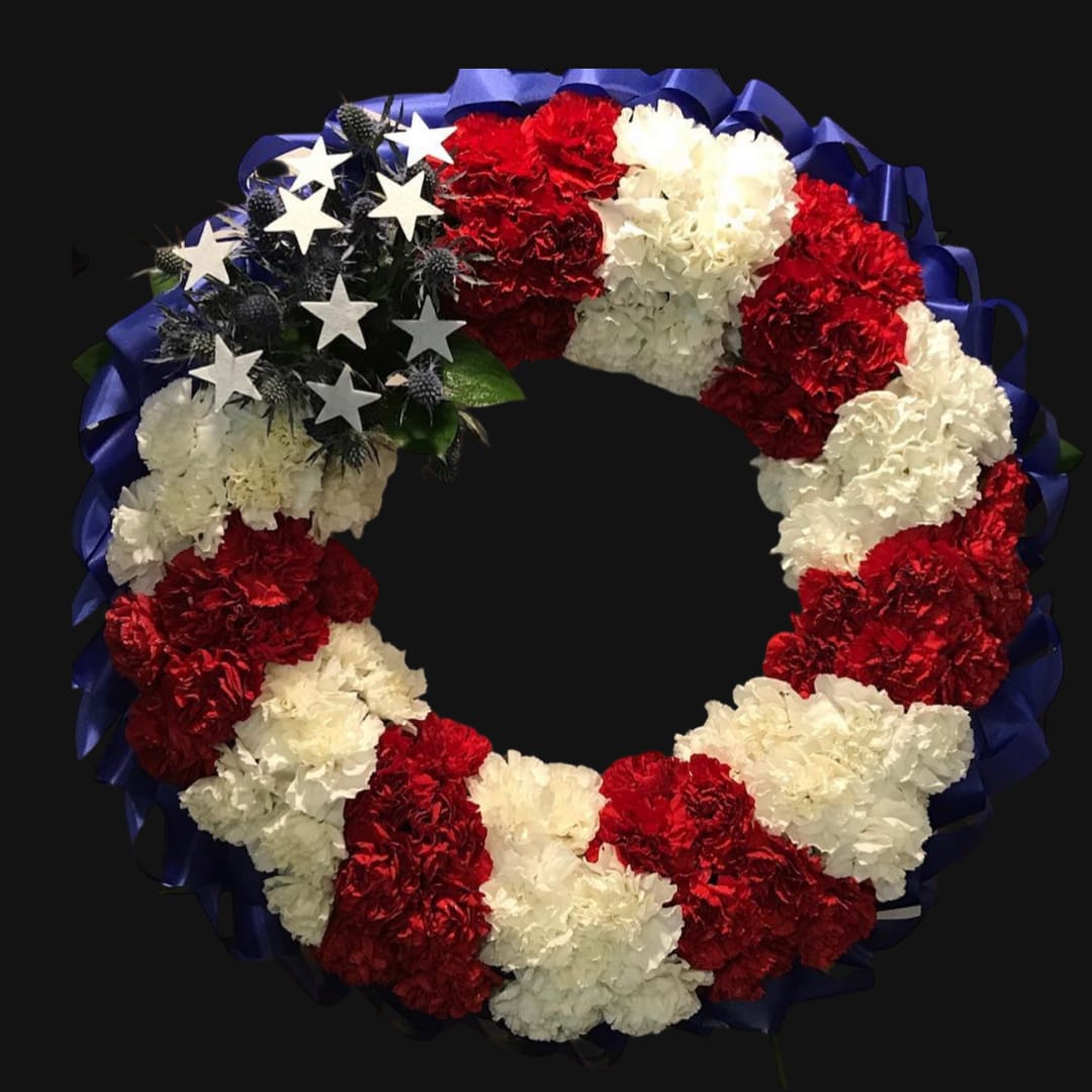 Red and white carnation wreath with blue ribbon and star accents