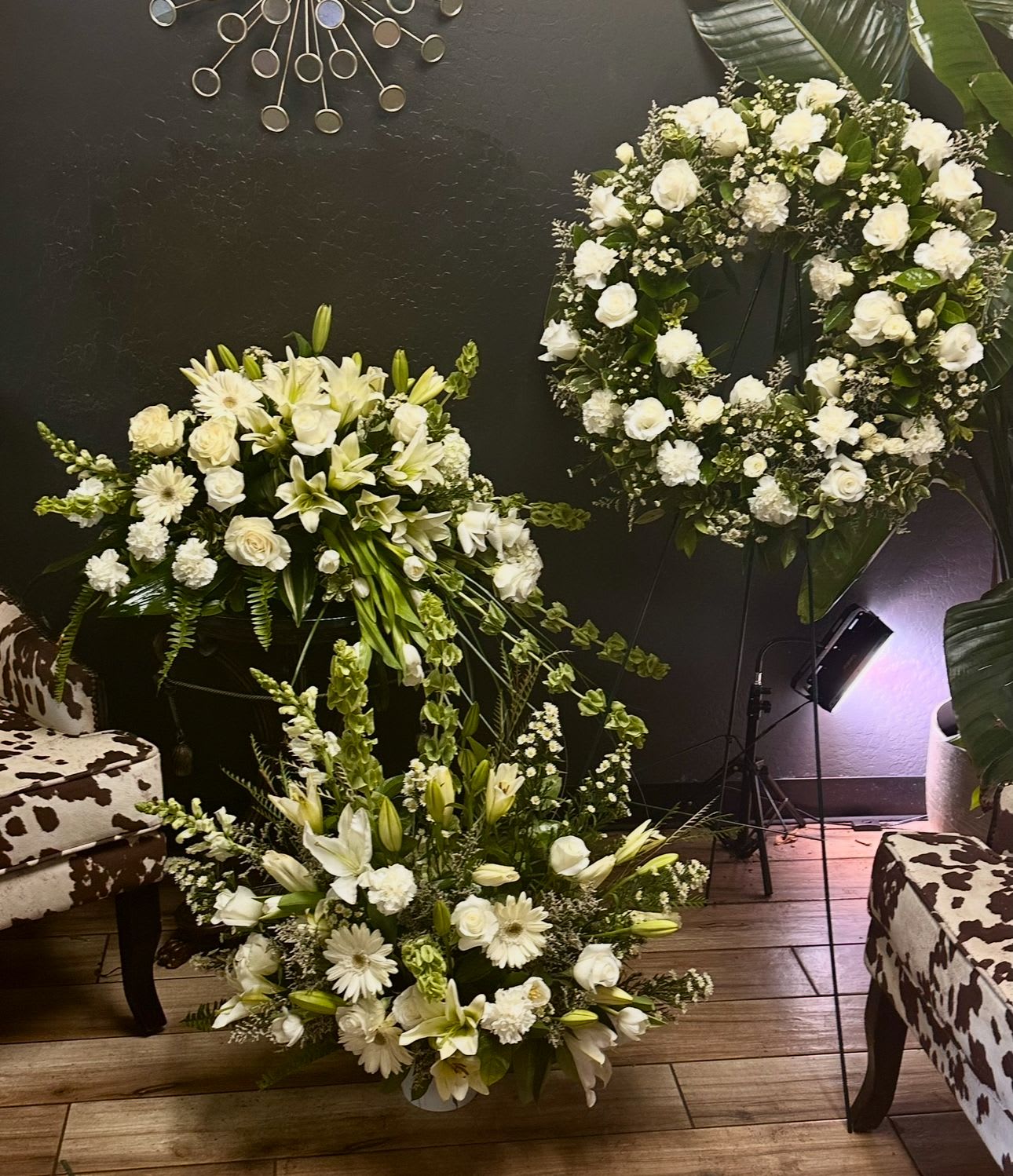 White floral wreath and two matching arrangements with lilies and roses