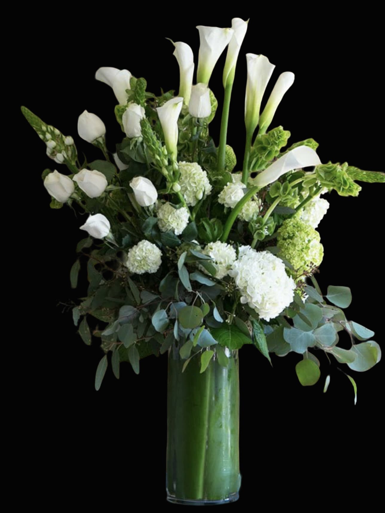 White calla lilies and hydrangeas in a tall glass vase