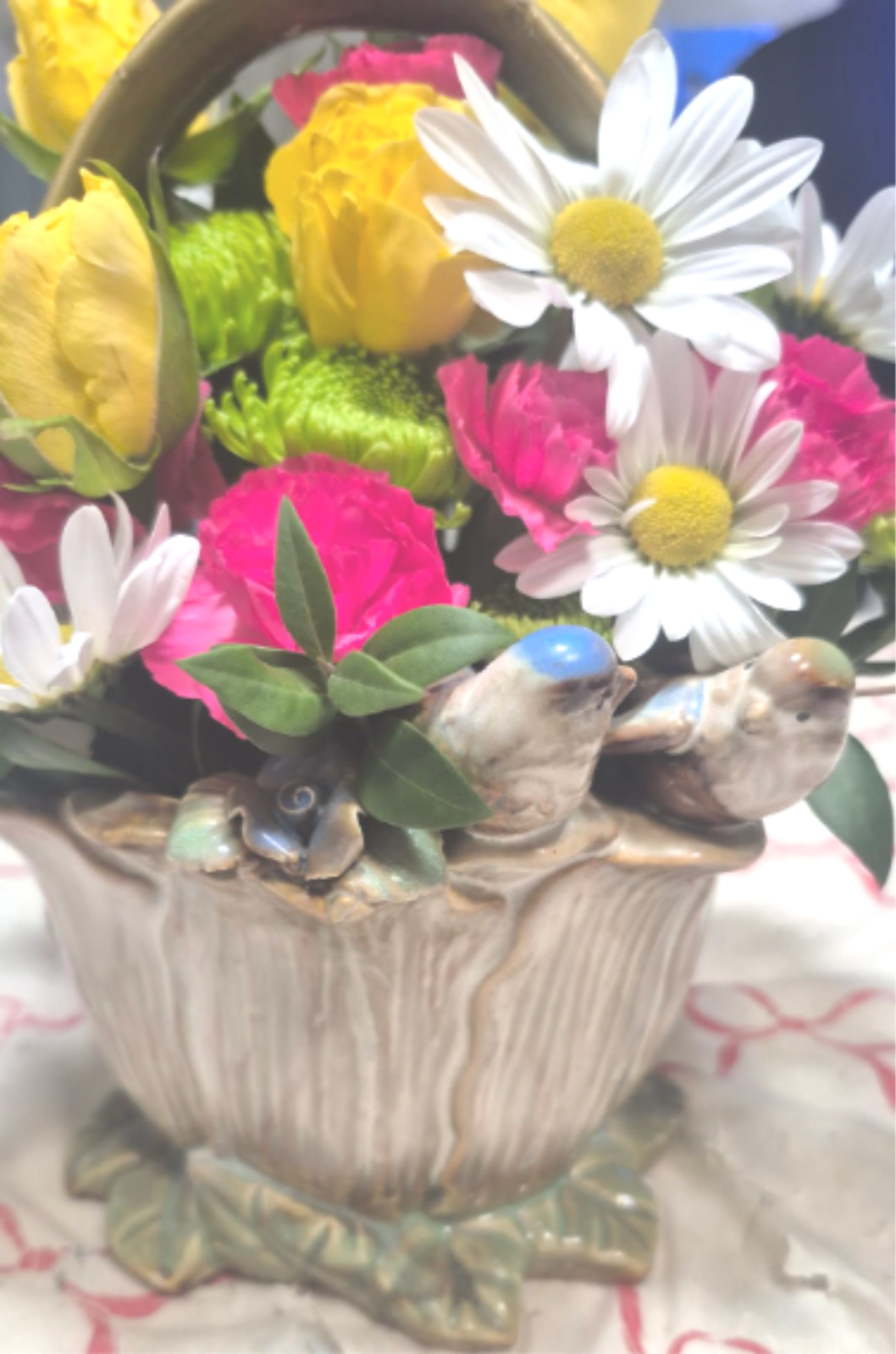 Colorful mix of yellow roses, pink carnations, and white daisies in a ceramic bird planter
