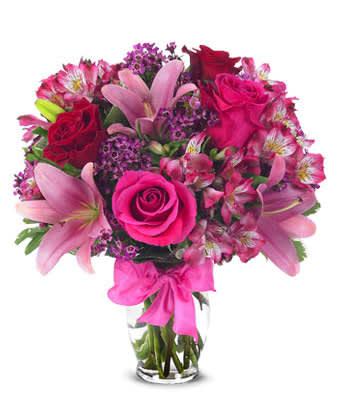European Romance Bouquet - This flirtatious combination of Asiatic lilies, waxflower, alstroemeria and roses makes a thoughtful gift they'll not soon forget. A pretty pink ribbon and clear fluted glass vase add to the romantic look. Small Measures 13"H by 11"L. Medium Measures 14"H by 12"L. Large Measures 15"H by 13"L.