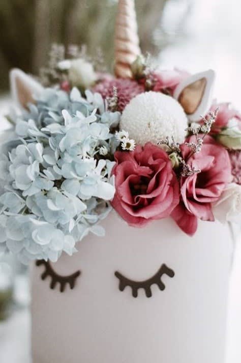 Floral arrangement in a white unicorn container with pink and blue blooms