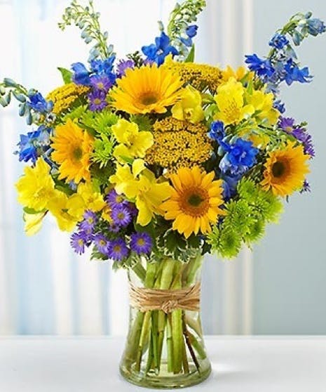 Bright mixed bouquet of yellow and blue flowers in a glass vase