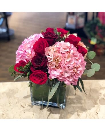 Red roses and pink hydrangeas in a square glass vase