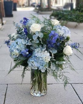 Blue and white floral arrangement in a clear glass vase