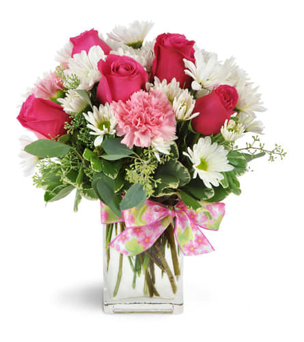 Pink roses and white daisies in a clear glass vase with a pink ribbon