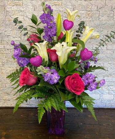 Bouquet of pink roses, white lilies, and purple flowers in a purple vase
