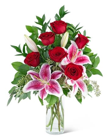 Red roses and pink lilies arranged in a clear glass vase