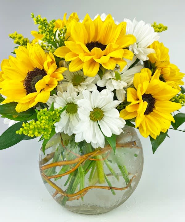 Bouquet of yellow sunflowers and white daisies in a round glass vase