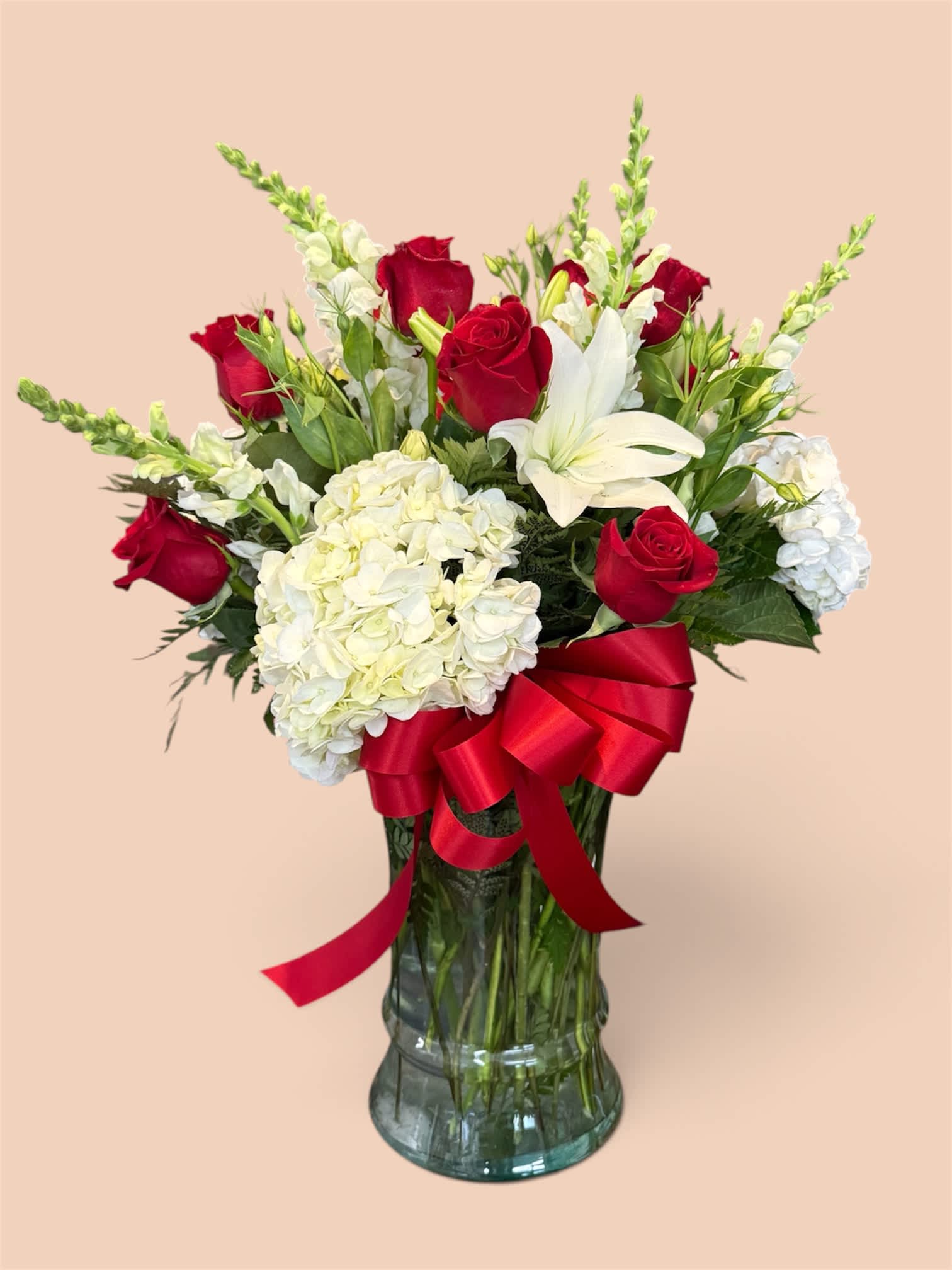 Red roses and white lilies in a glass vase with a red ribbon