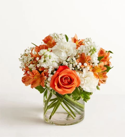 Orange and white mixed flower bouquet in a clear glass vase