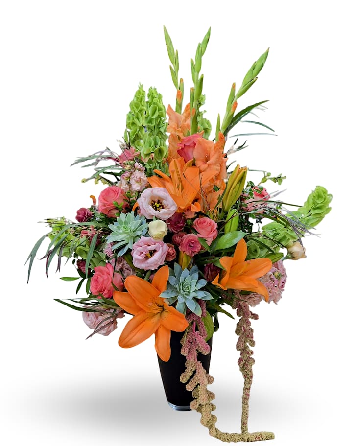 Tall mixed bouquet with orange lilies, pink roses, and green blooms in a black vase