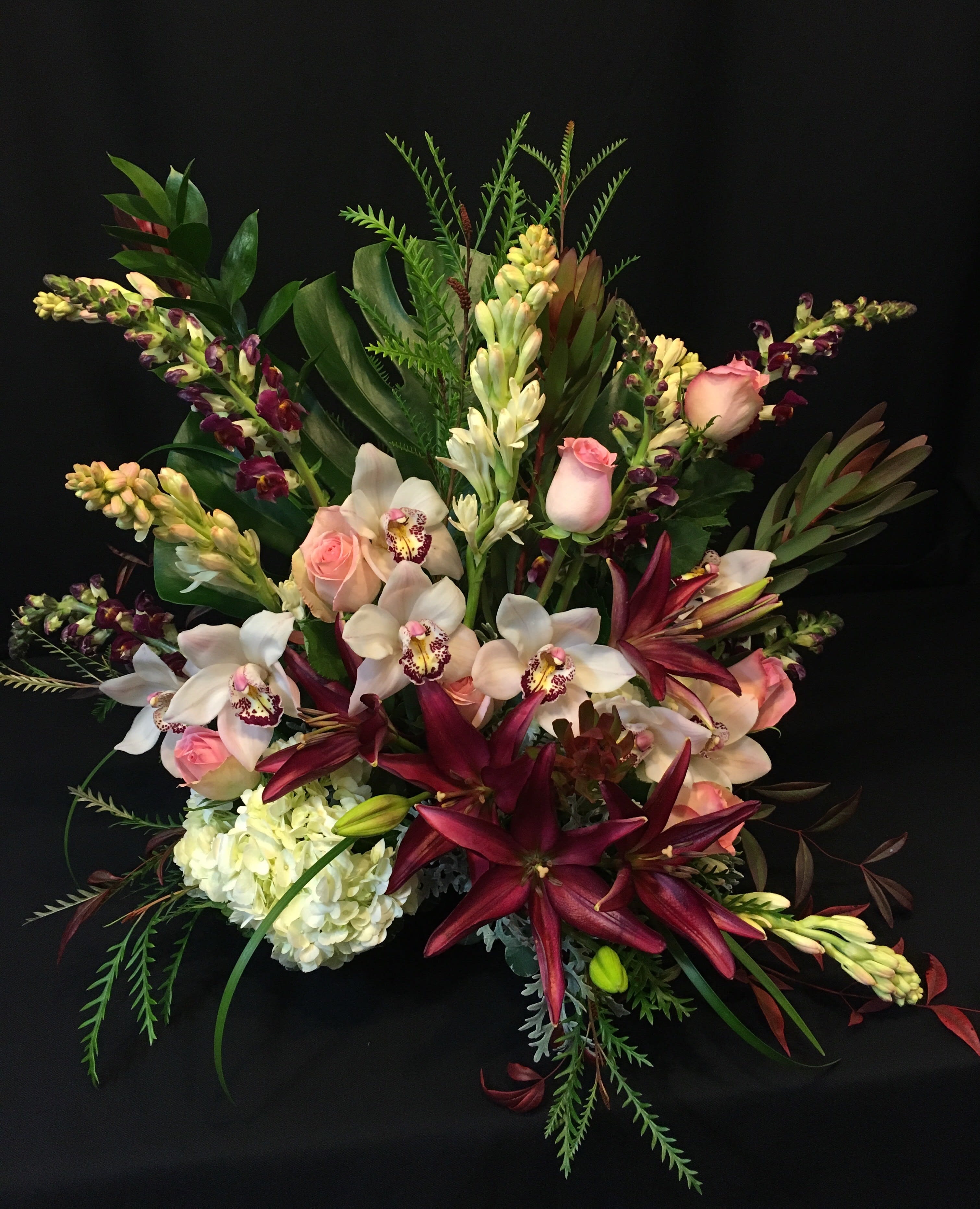 Tropical Display of Roses, Lilies and Orchids - Exquisite display of lavish flowers suitable for an anniversary or valentine's day. We use tropical foliage and cymbidium orchids, plus roses, lilies and seasonal flowers. The most impressive romantic bouquet you will ever send.    Order a couple weeks in advance; these flowers can be difficult to get certain times of the year.