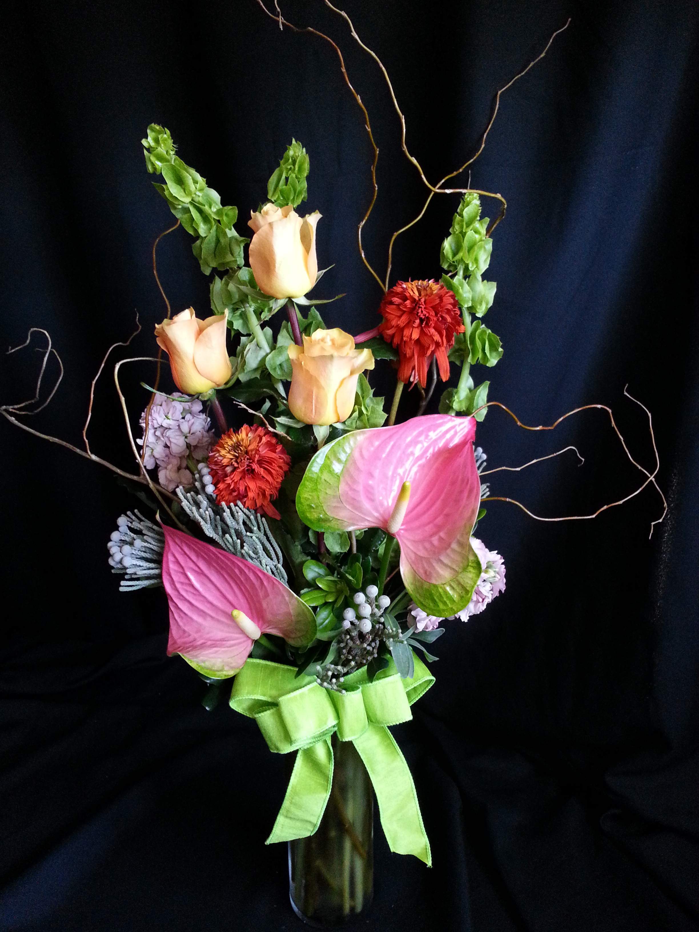 Elegant Anthurium with Roses and Willow - A lovely mellow toned romantic arrangement of exotic flowers and our most premium long stem large import roses.  Flowers and colors will vary.  Shown here: anthurium, bells of Ireland, echinacea, brunia, stock and Colombian roses.  Excellent choice for those who desire a more exotic design, but still appreciate high quality roses.  Beautiful as an Anniversary bouquet