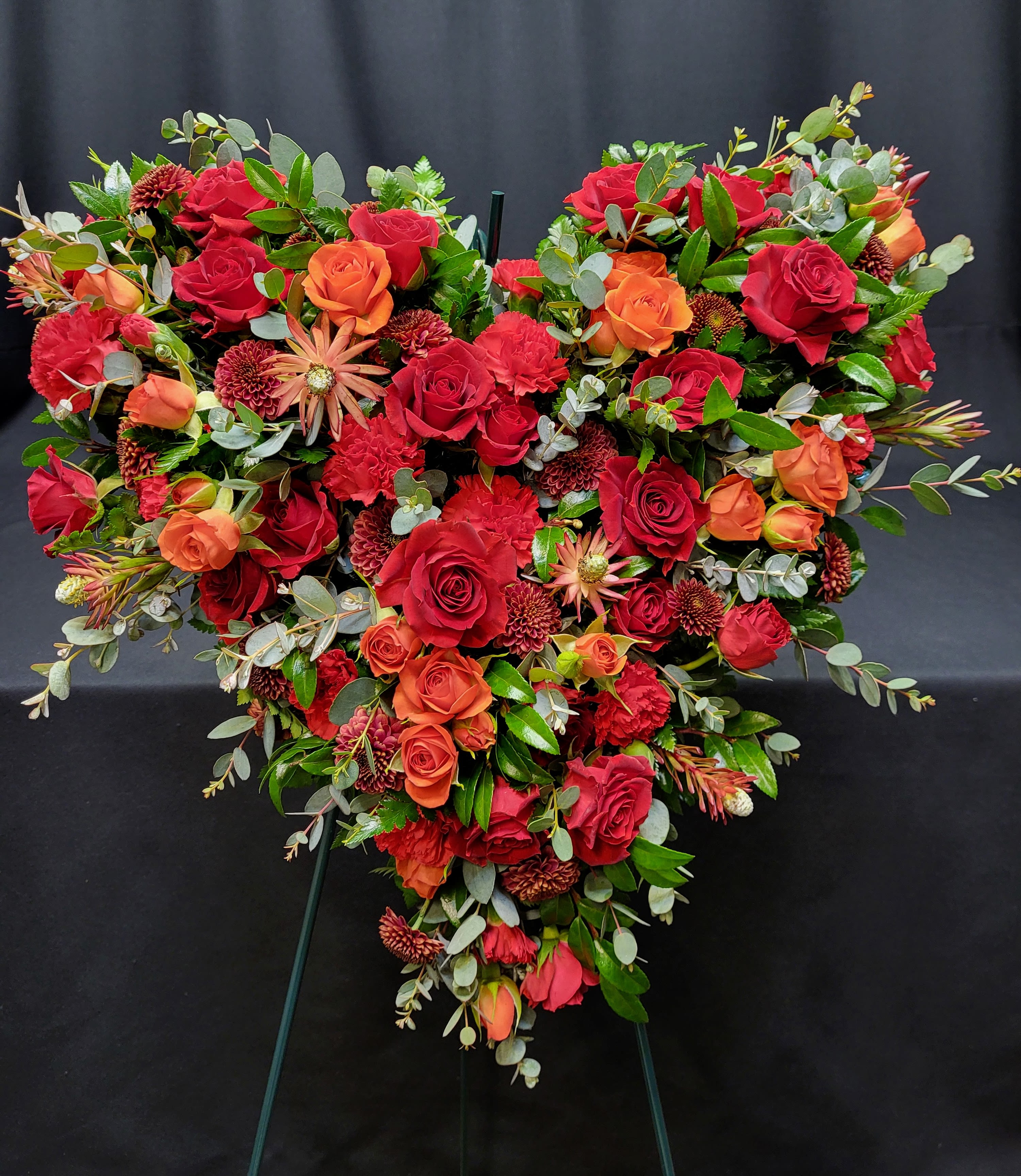 Heart-shaped floral spray with red and orange roses