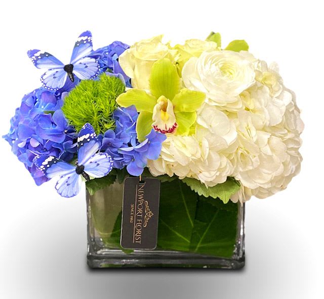 Blue and white floral arrangement in a square glass vase with butterfly accents