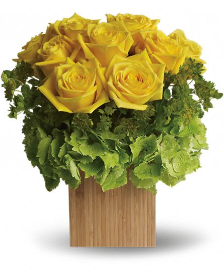 Yellow roses arranged in a wooden cube vase with green hydrangea