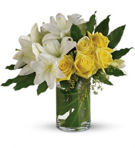 White lilies and yellow roses in a clear glass vase