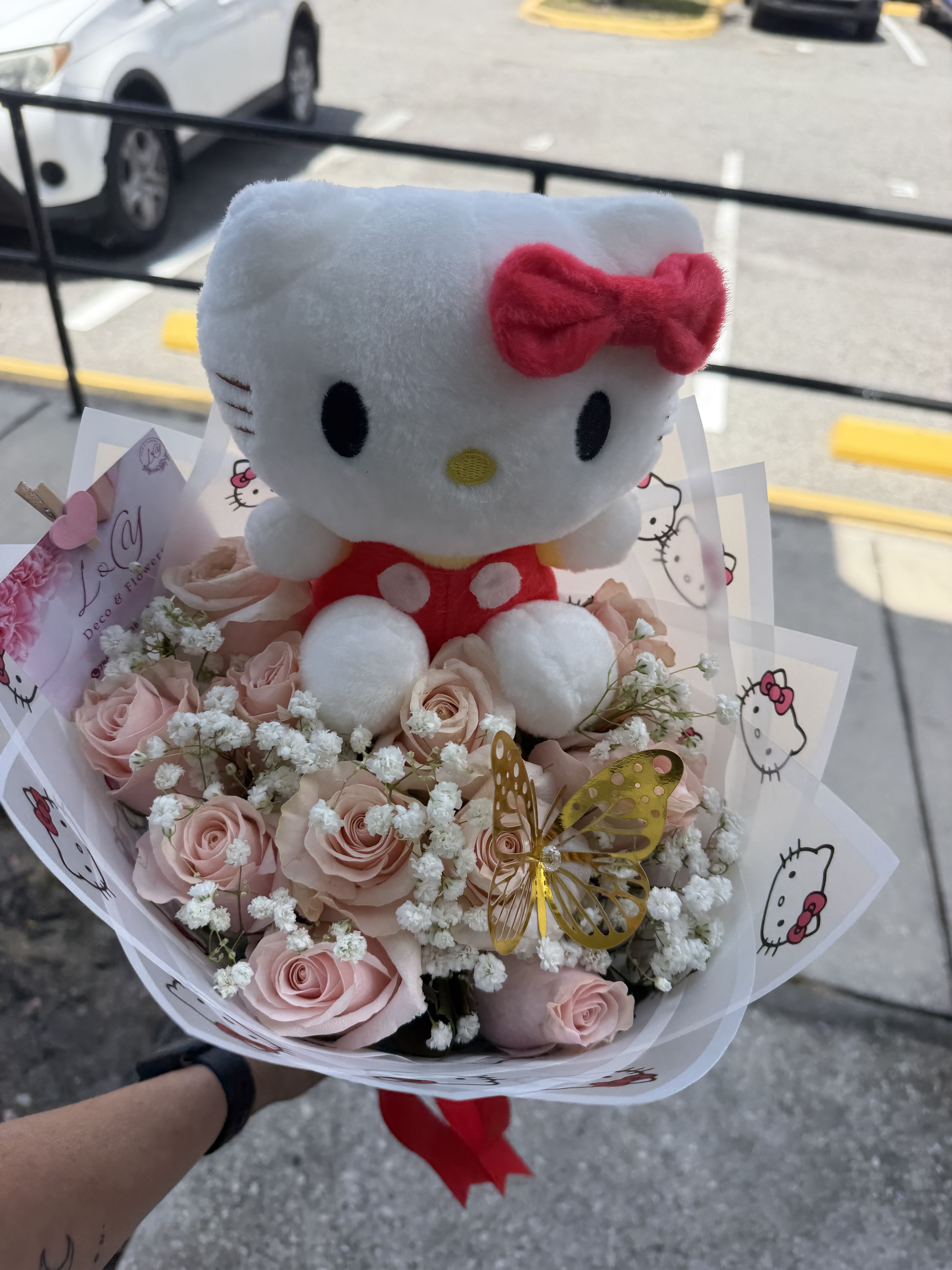 Mini Hello kitty Bouquet - Delicado y encanador ramo Que combina la ternura de hello kitty con la elegancia de las rosas rosadas premium. Diseñado con finos detalles de gypsophila (baby’s breath) y un toque especial de mariposas decorativa,envuelto en papel en tonos rosado y azul q resaltan su dulzura.