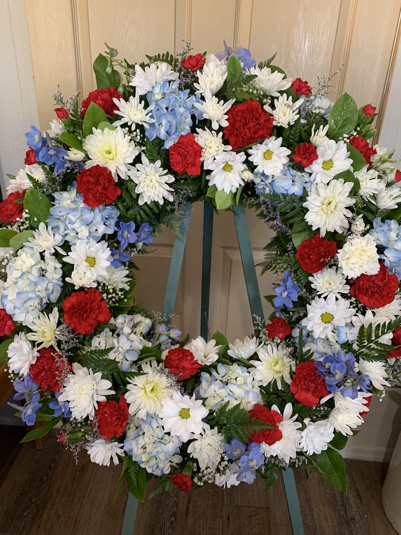Large floral wreath with red, white, and blue flowers on a stand