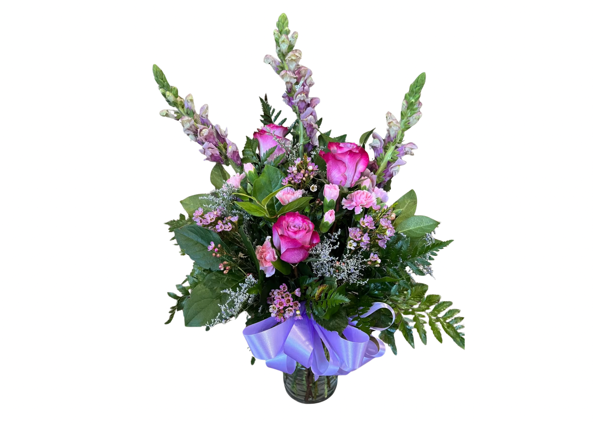 Mixed bouquet of pink roses, carnations, and tall snapdragons in a glass vase with a lavender ribbon bow.