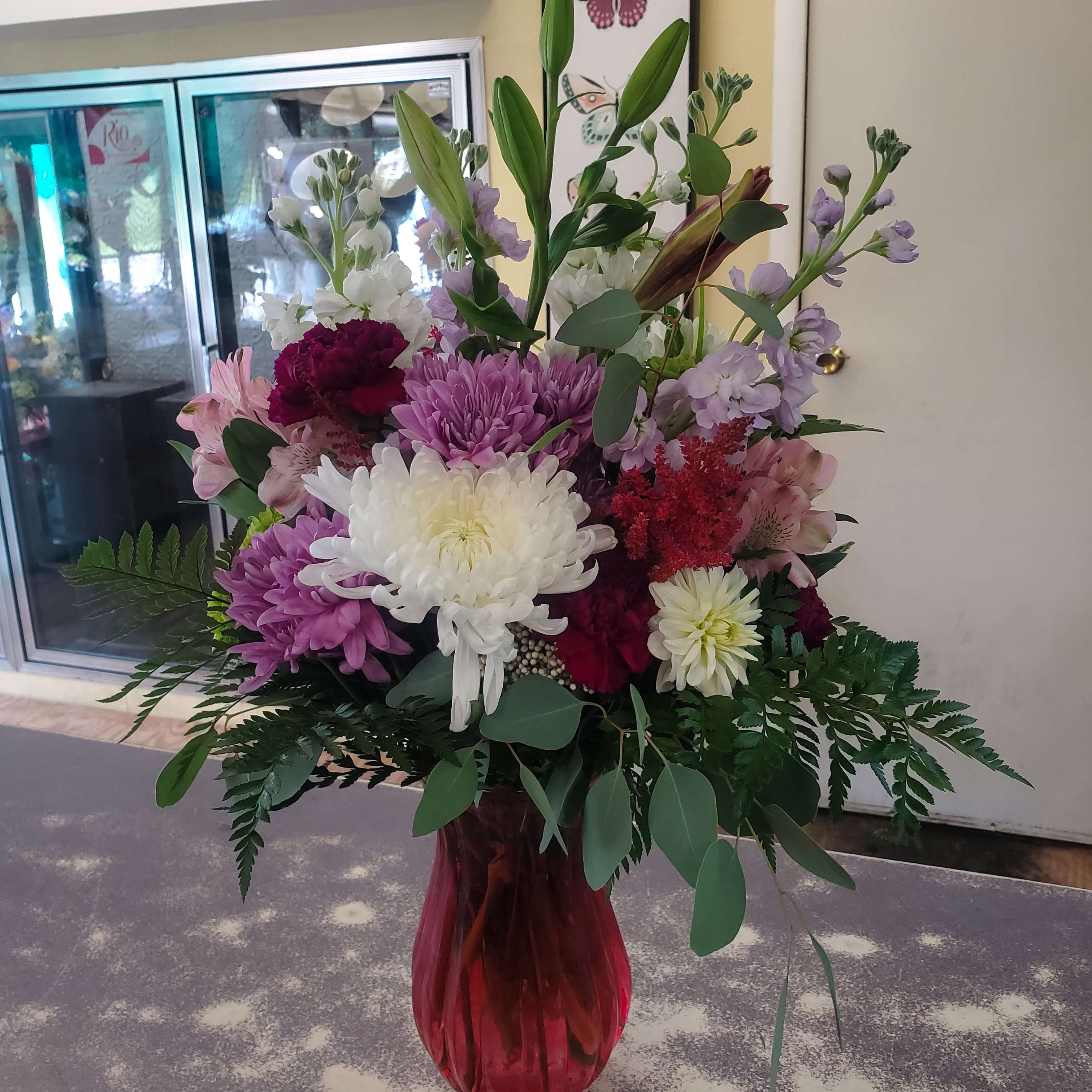 Mixed bouquet of white, pink, and purple flowers in a red glass vase