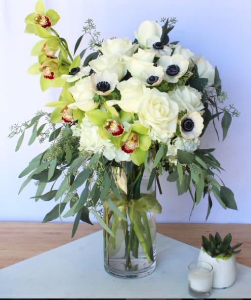 White roses and green orchids in a glass vase
