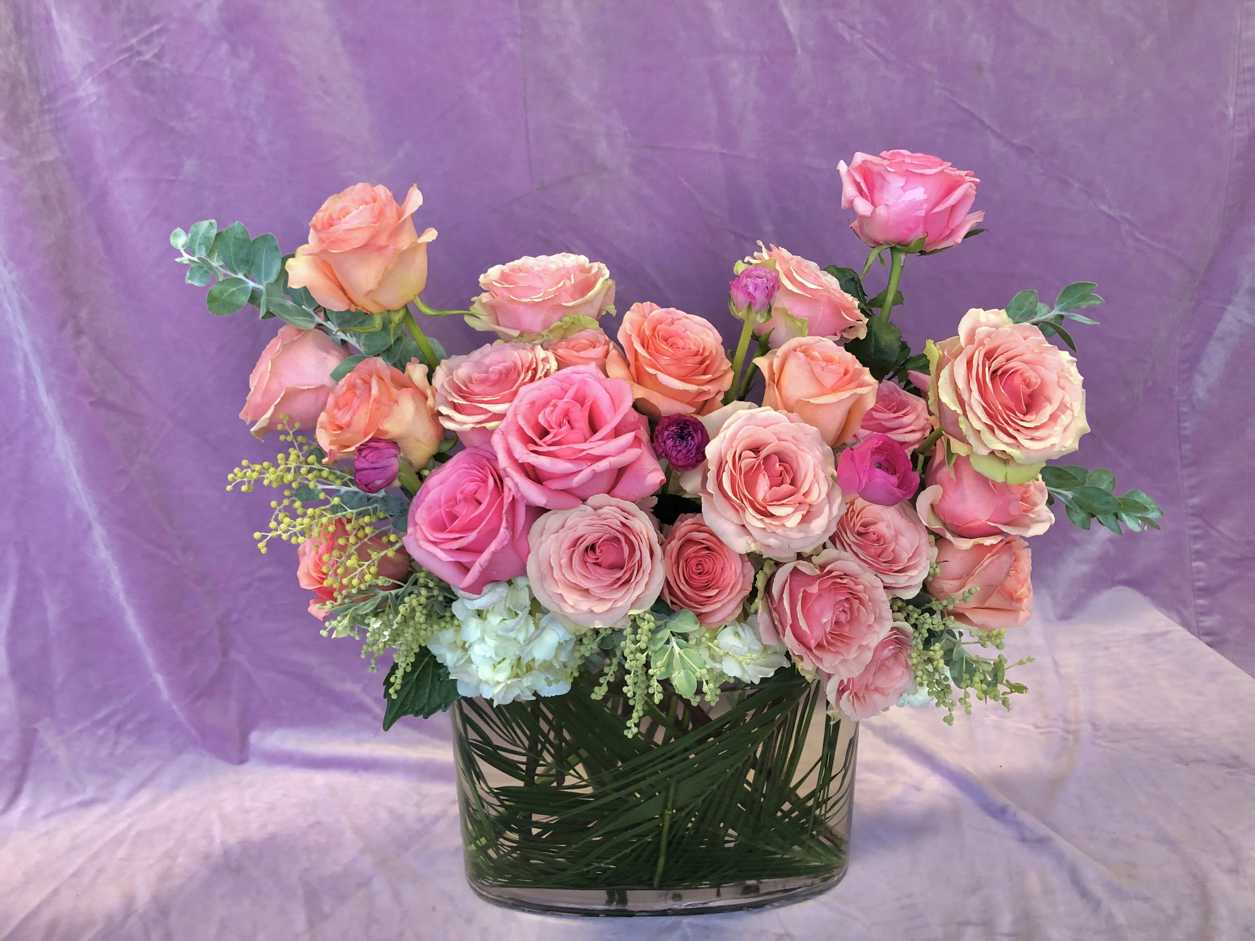 Pink and peach roses arranged in a clear glass vase