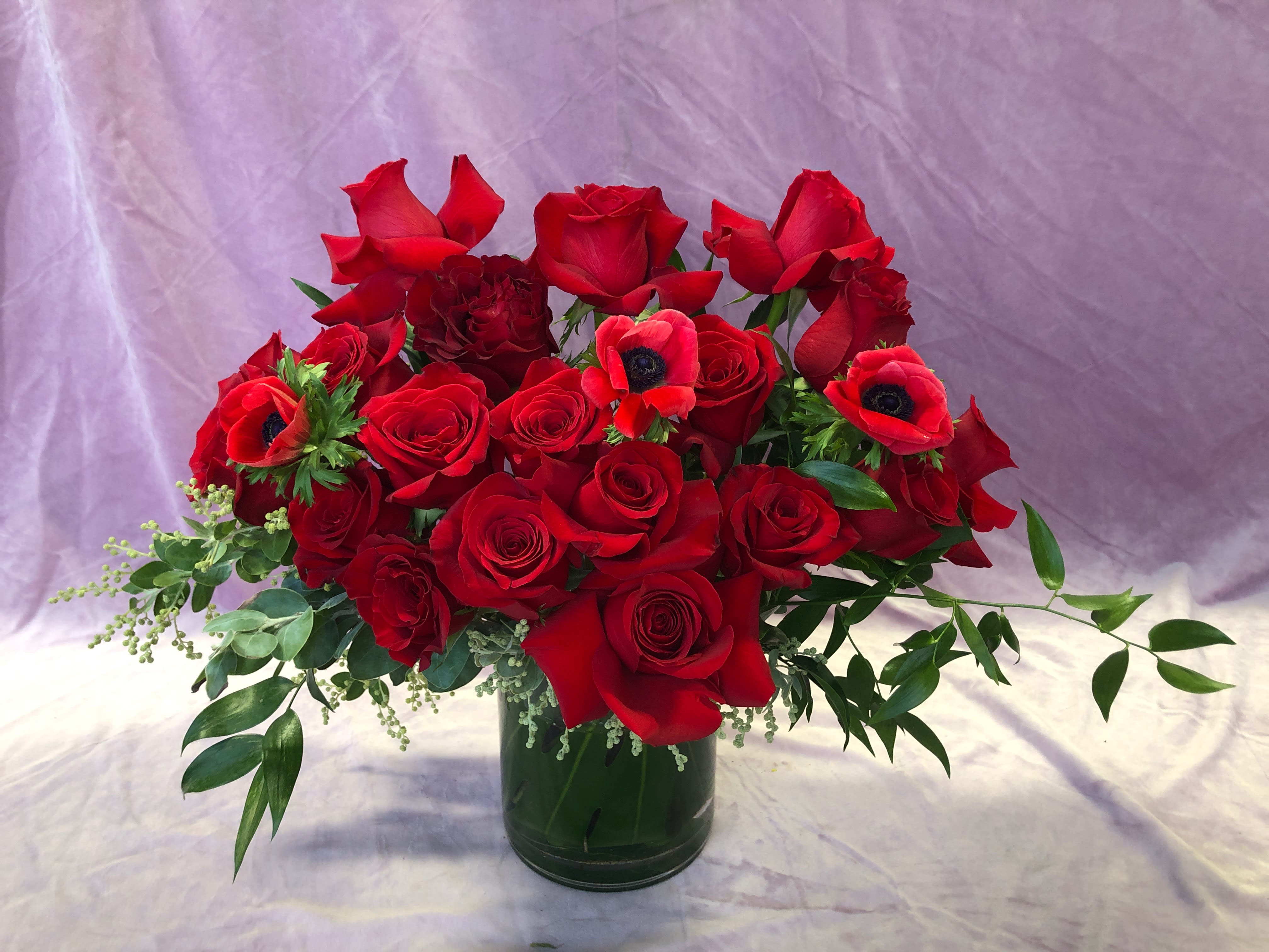 Red roses and anemones arranged in a glass vase