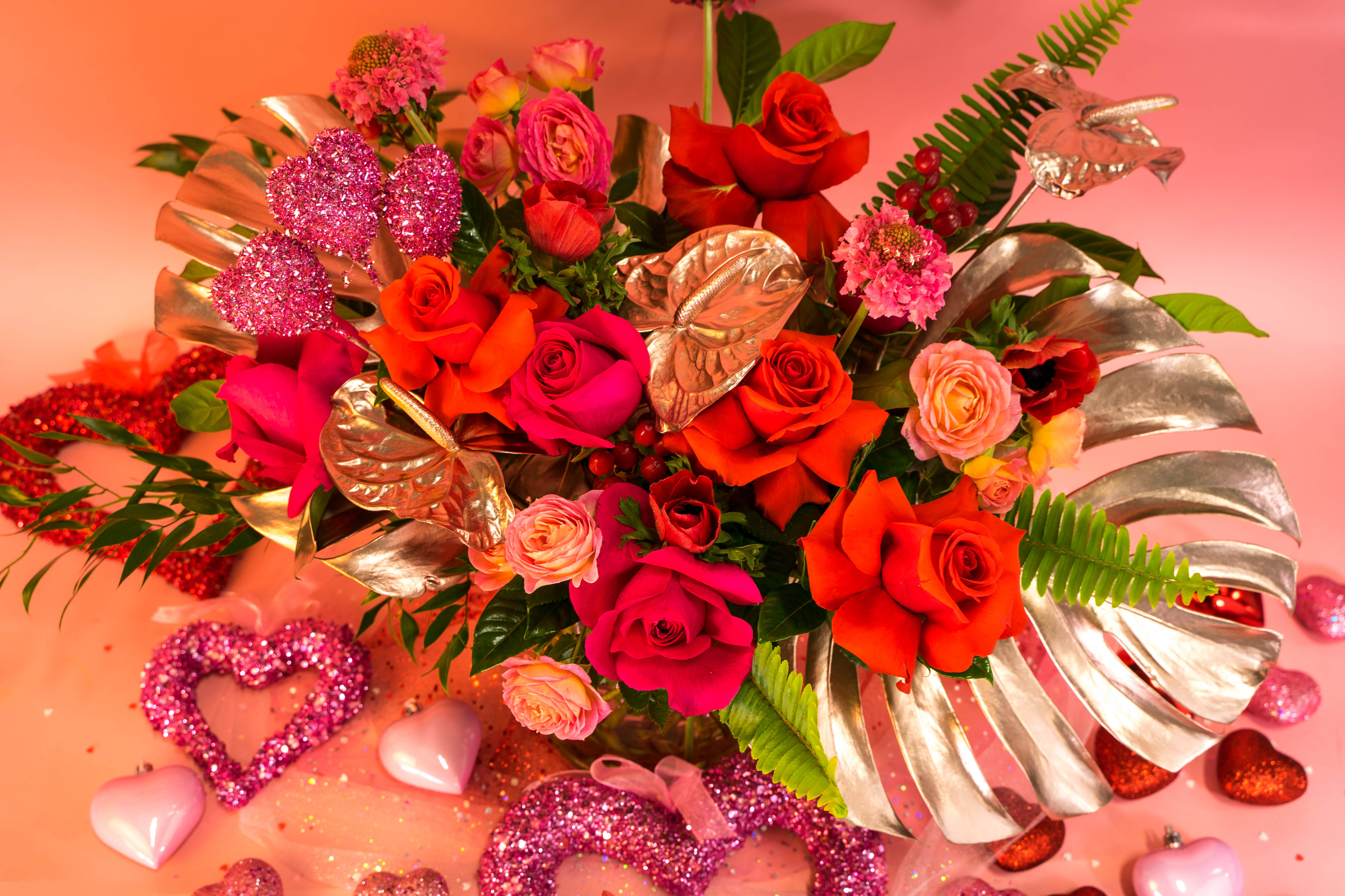 Bright bouquet of roses with metallic leaves and glitter heart decorations