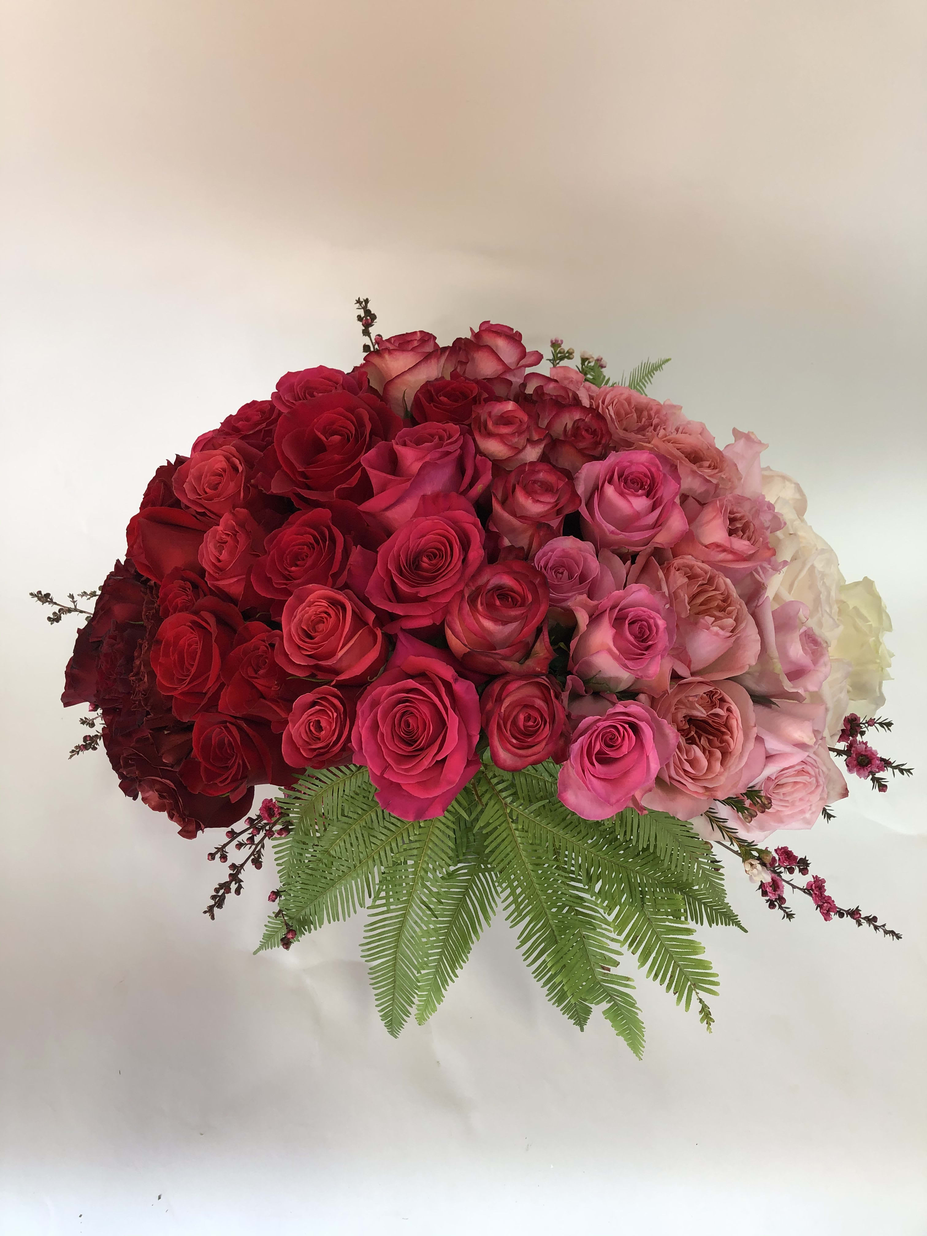 Large bouquet of red and pink roses with fern foliage