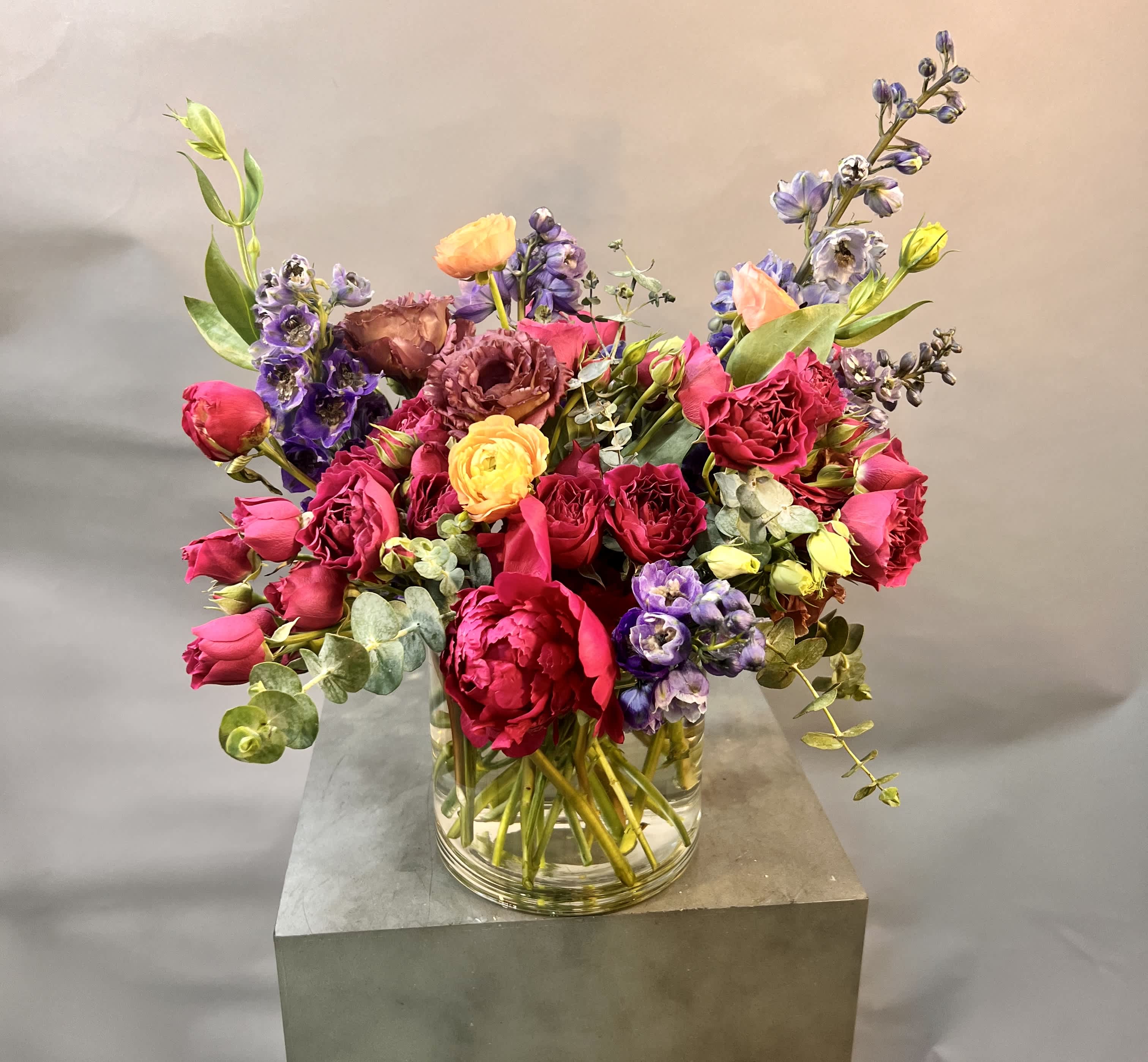 Mixed bouquet of pink, purple, and yellow flowers in a clear glass vase