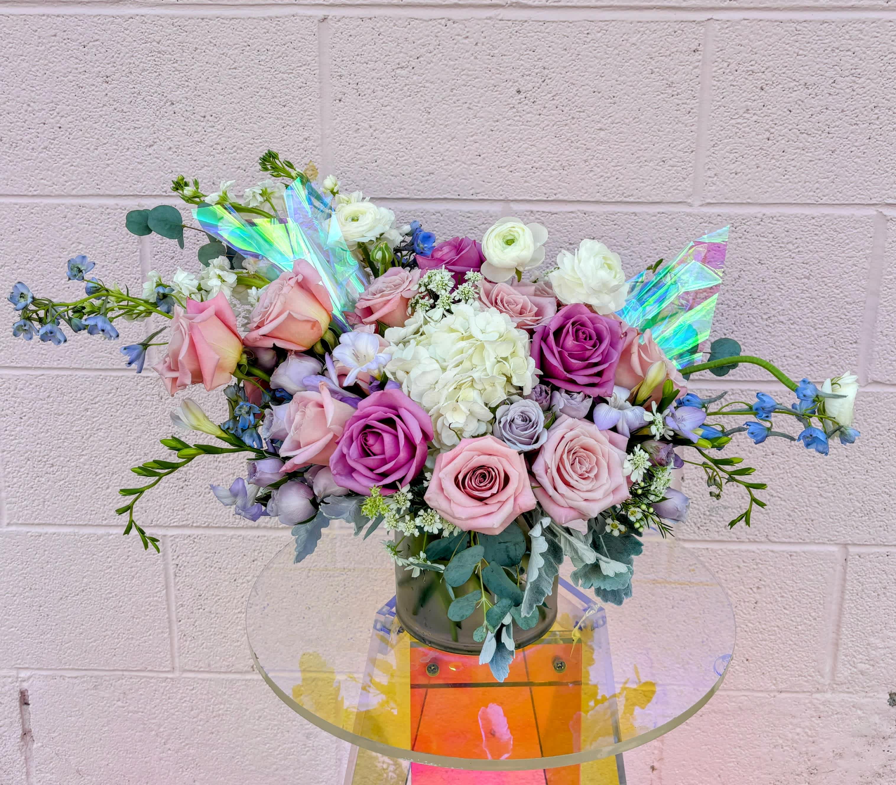 Bouquet of pink and purple roses with white blooms in a glass vase