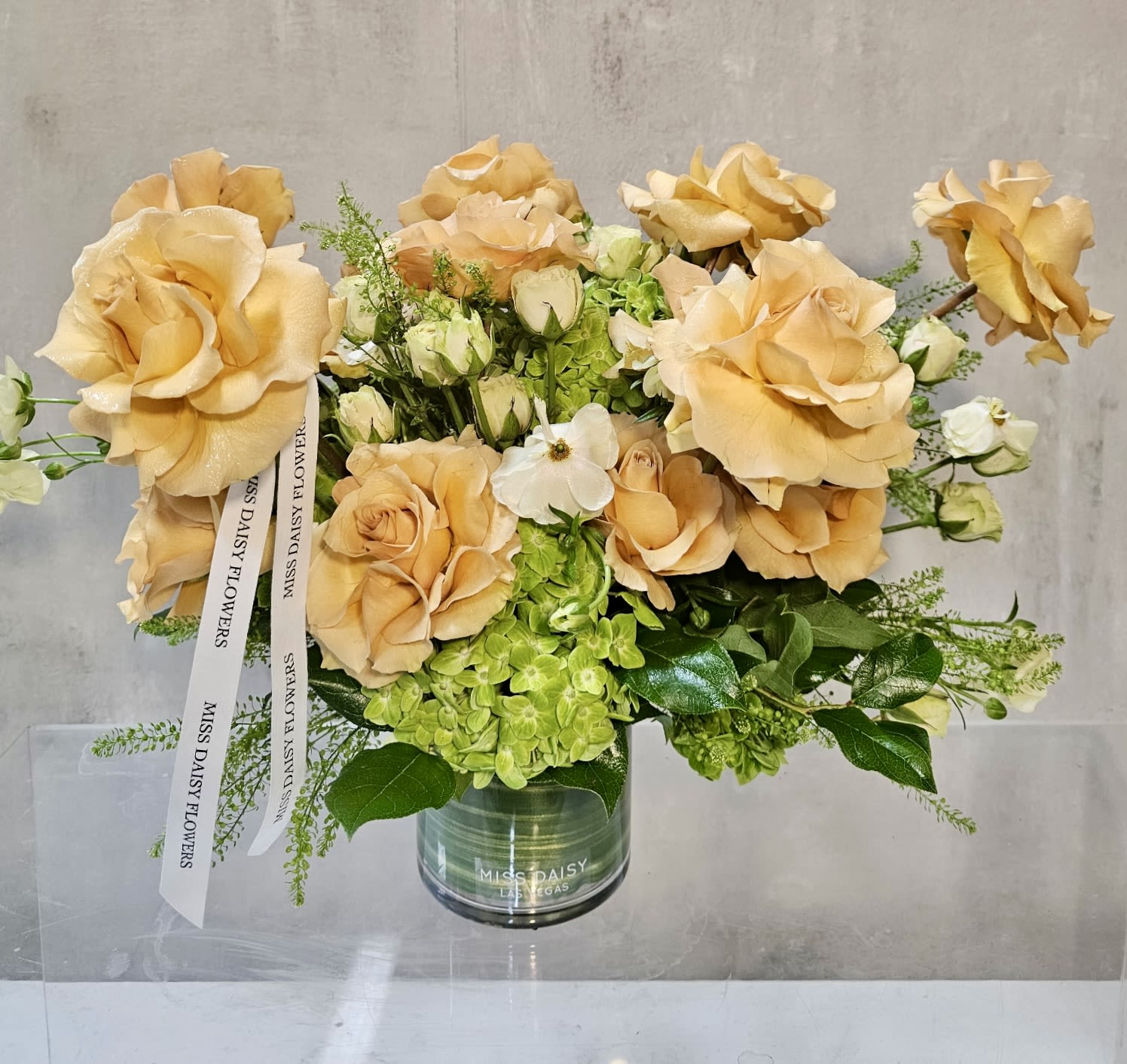 Peach roses and green hydrangeas in a glass vase