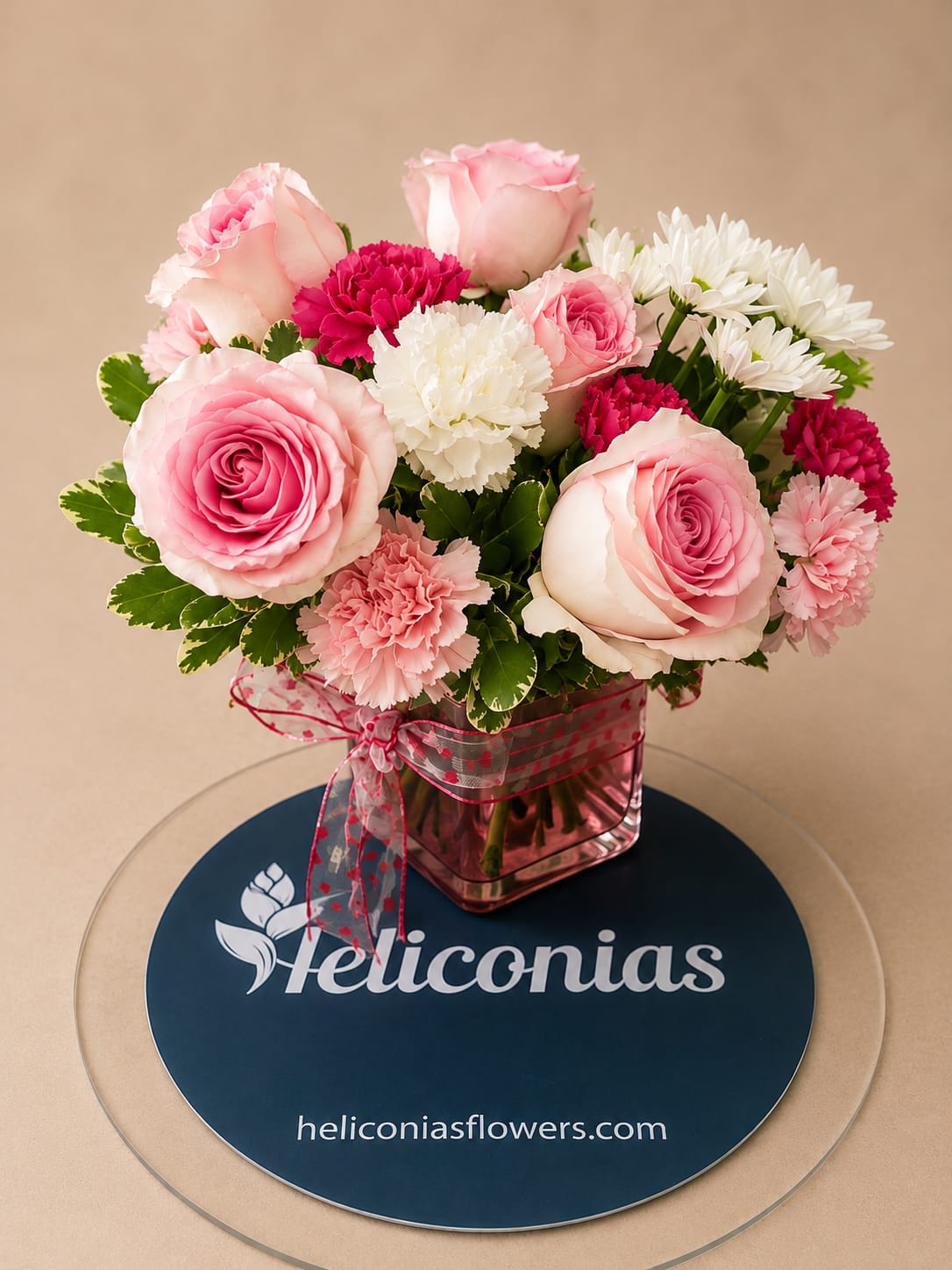 Pink roses and carnations arranged in a square glass vase