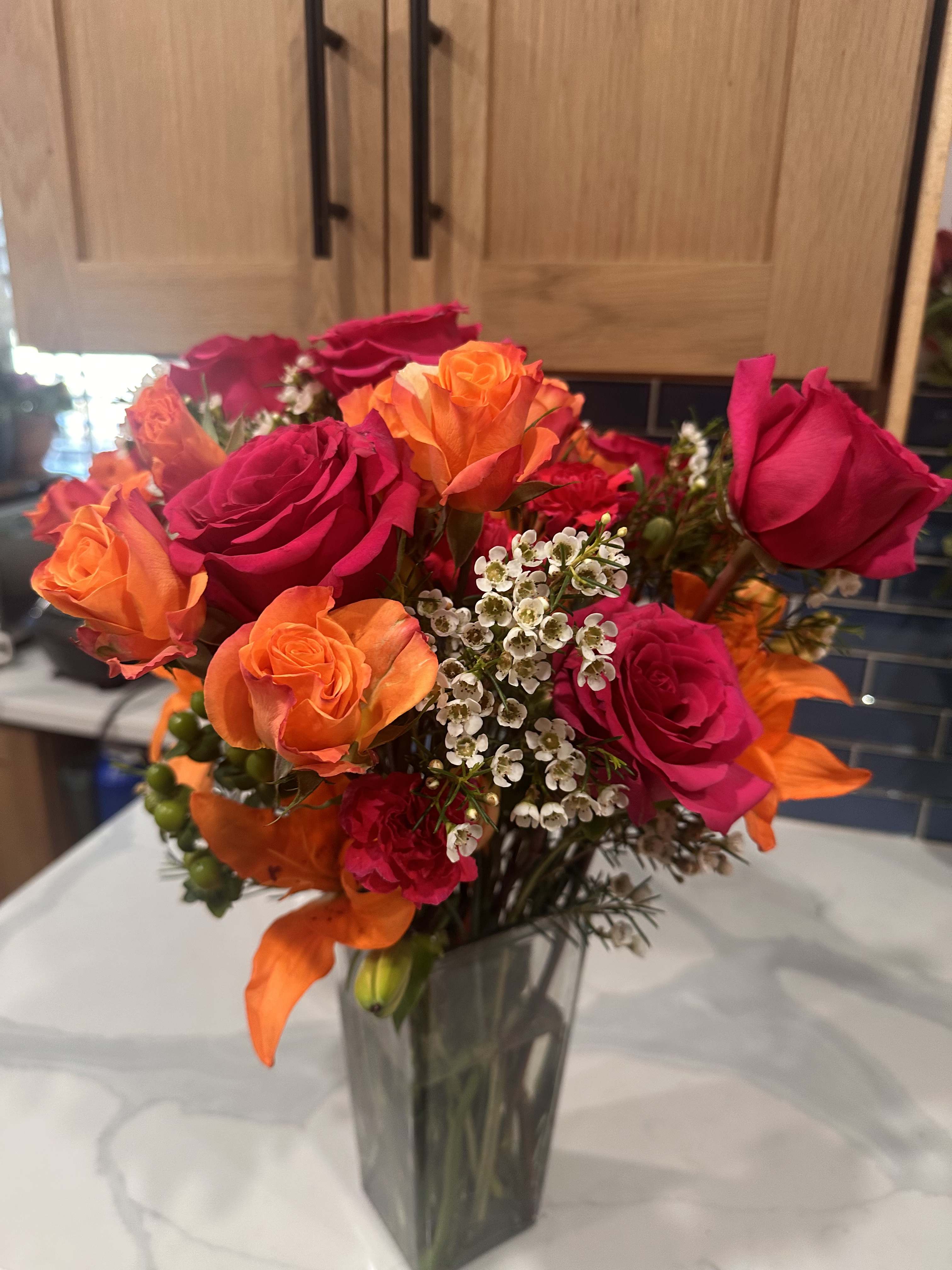 Bouquet of orange and hot pink roses in a clear glass vase