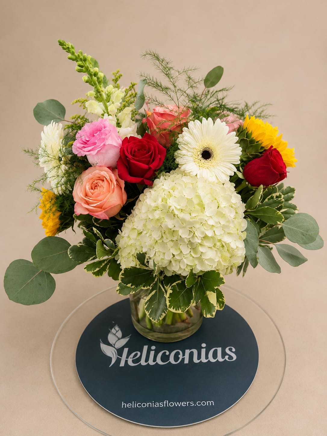 Mixed bouquet of roses, gerbera daisies, and hydrangea in a glass vase