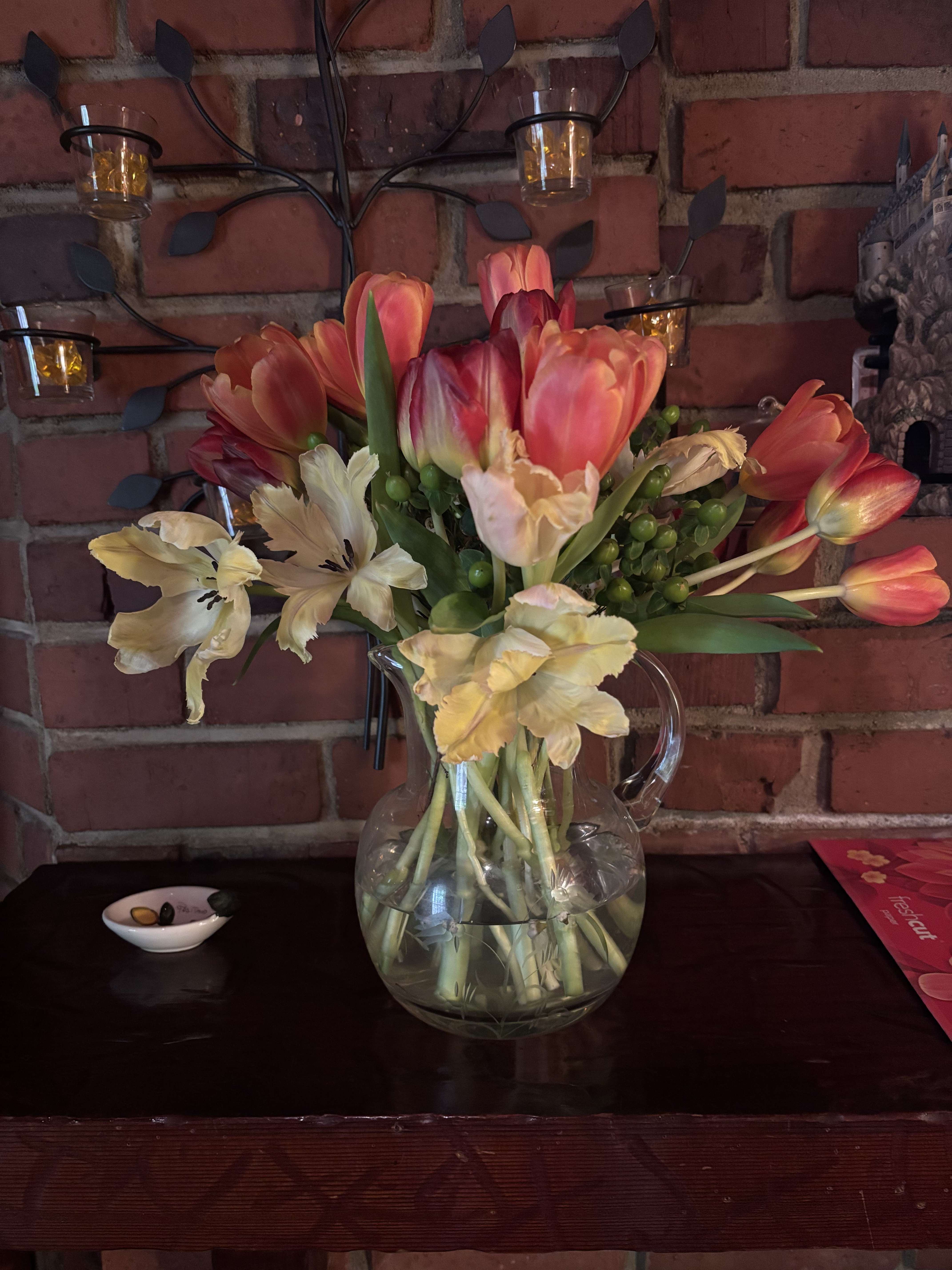 Tulip bouquet with pale cream flowers in a clear glass pitcher vase