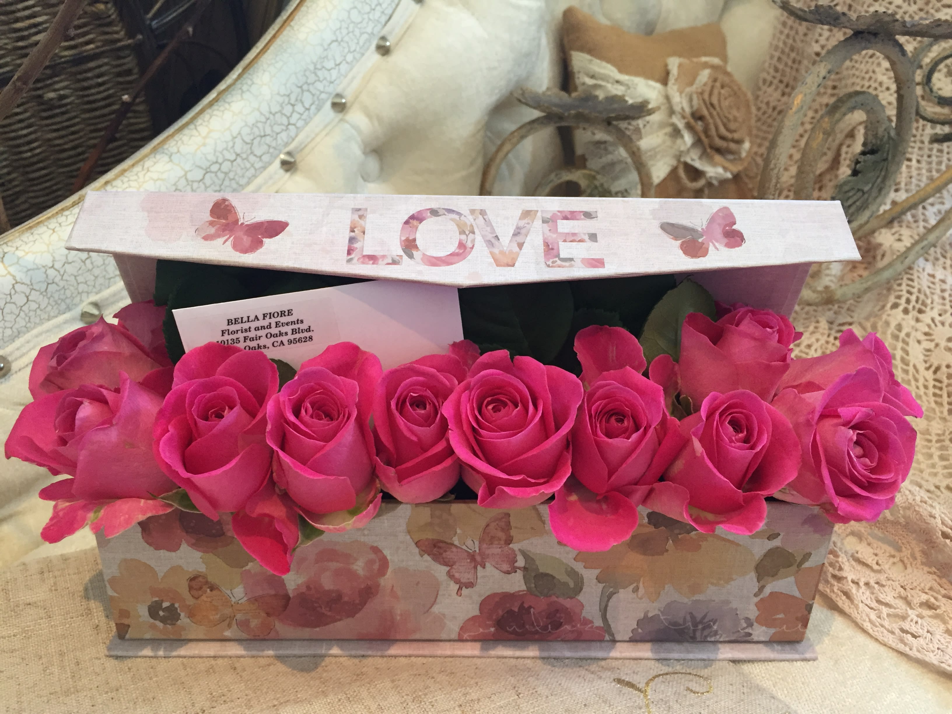 Pink roses arranged in a floral gift box with a LOVE lid