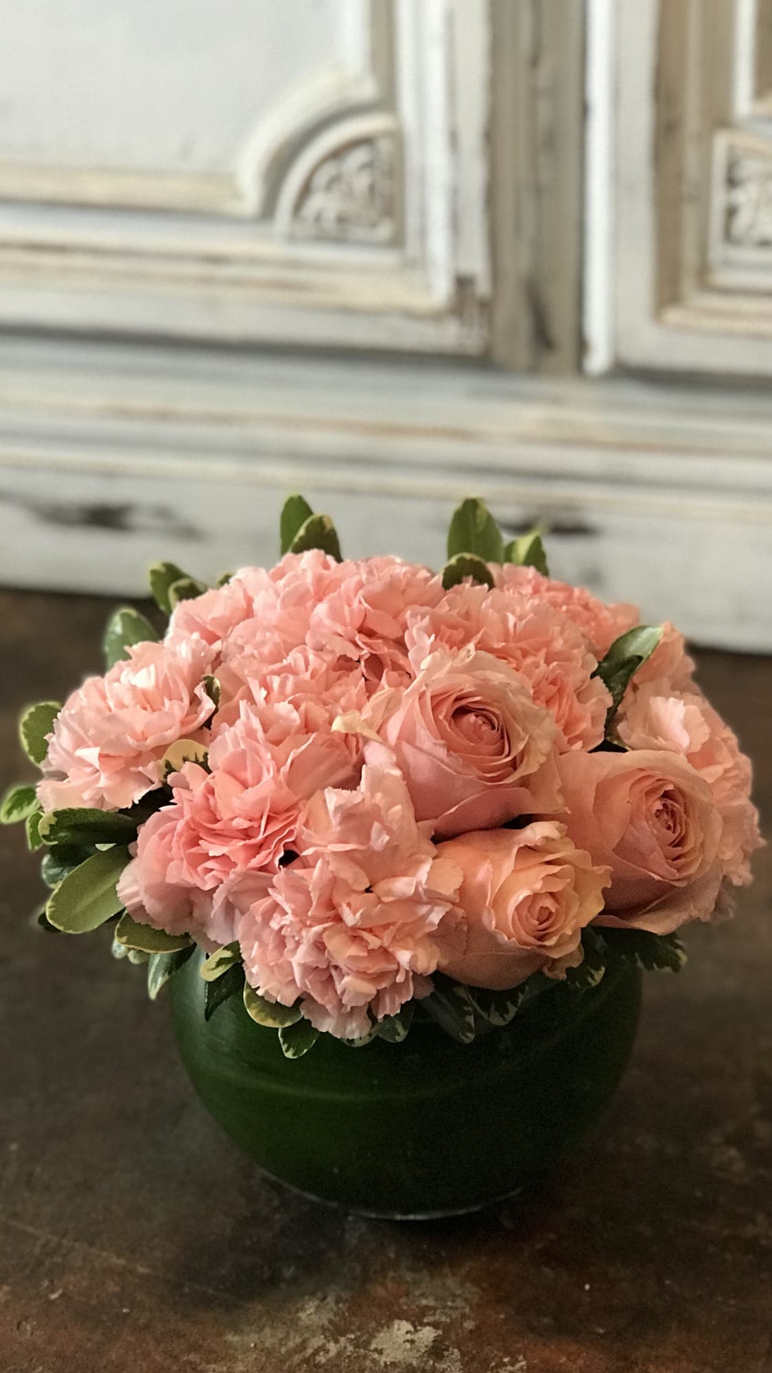 Pink roses and carnations arranged in a green vase