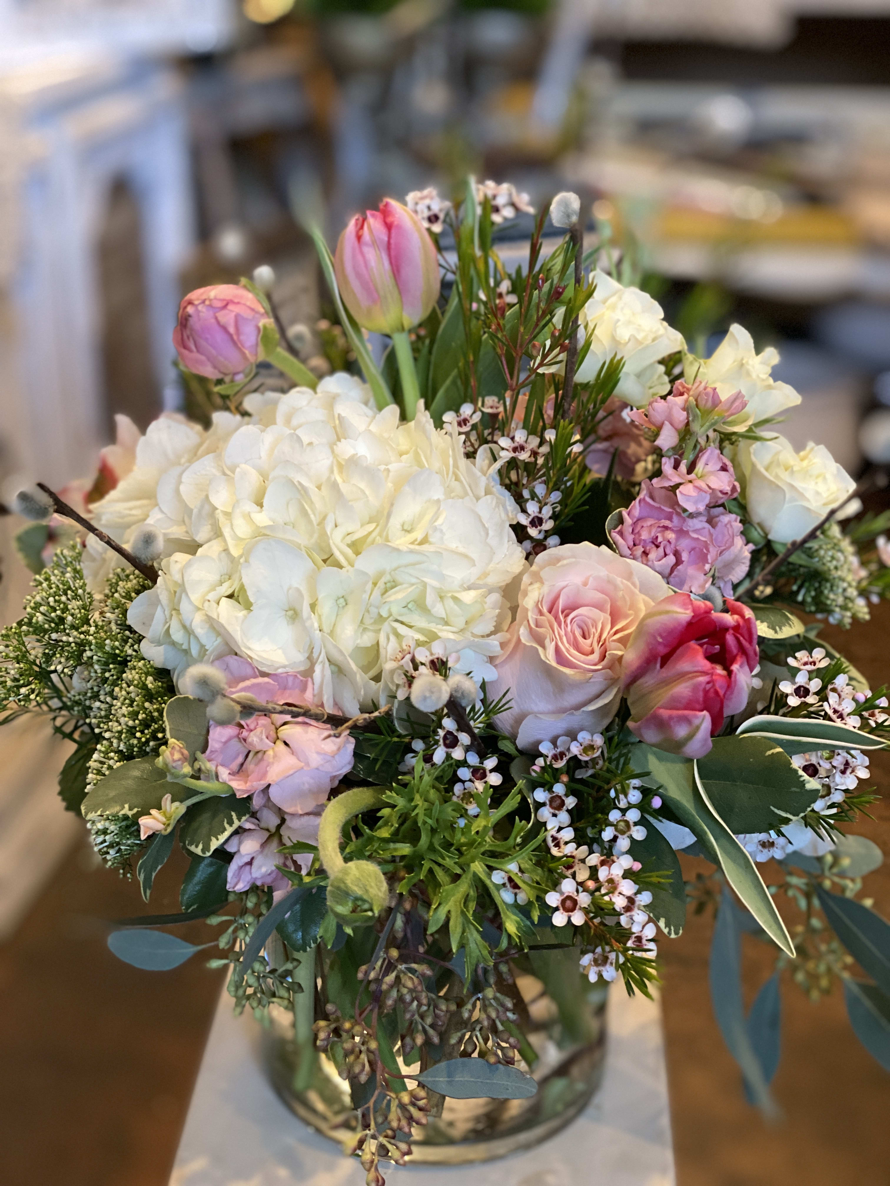Bouquet of white hydrangeas, pink roses, and tulips in a glass vase