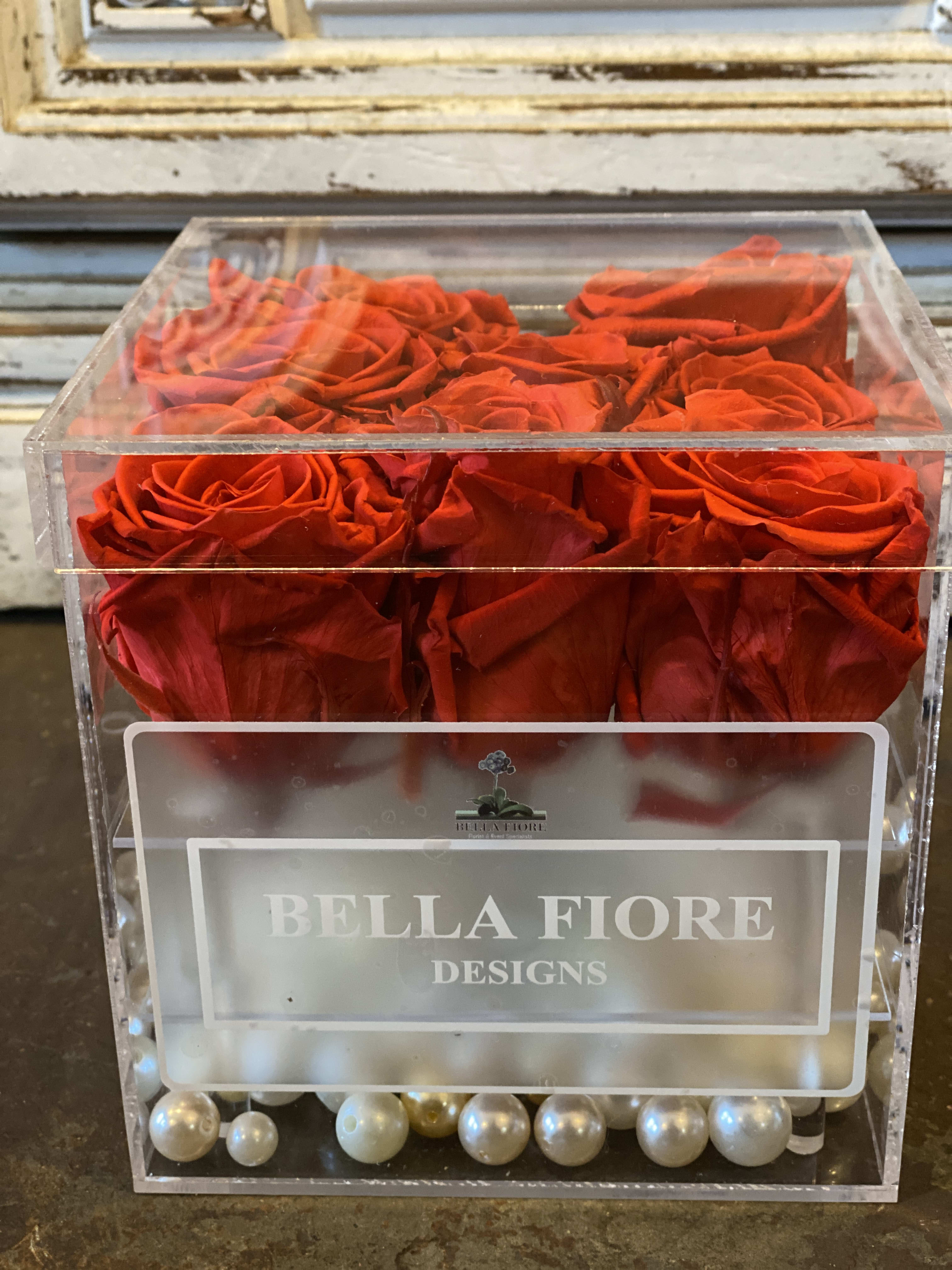 Red roses in a clear acrylic box with pearl accents