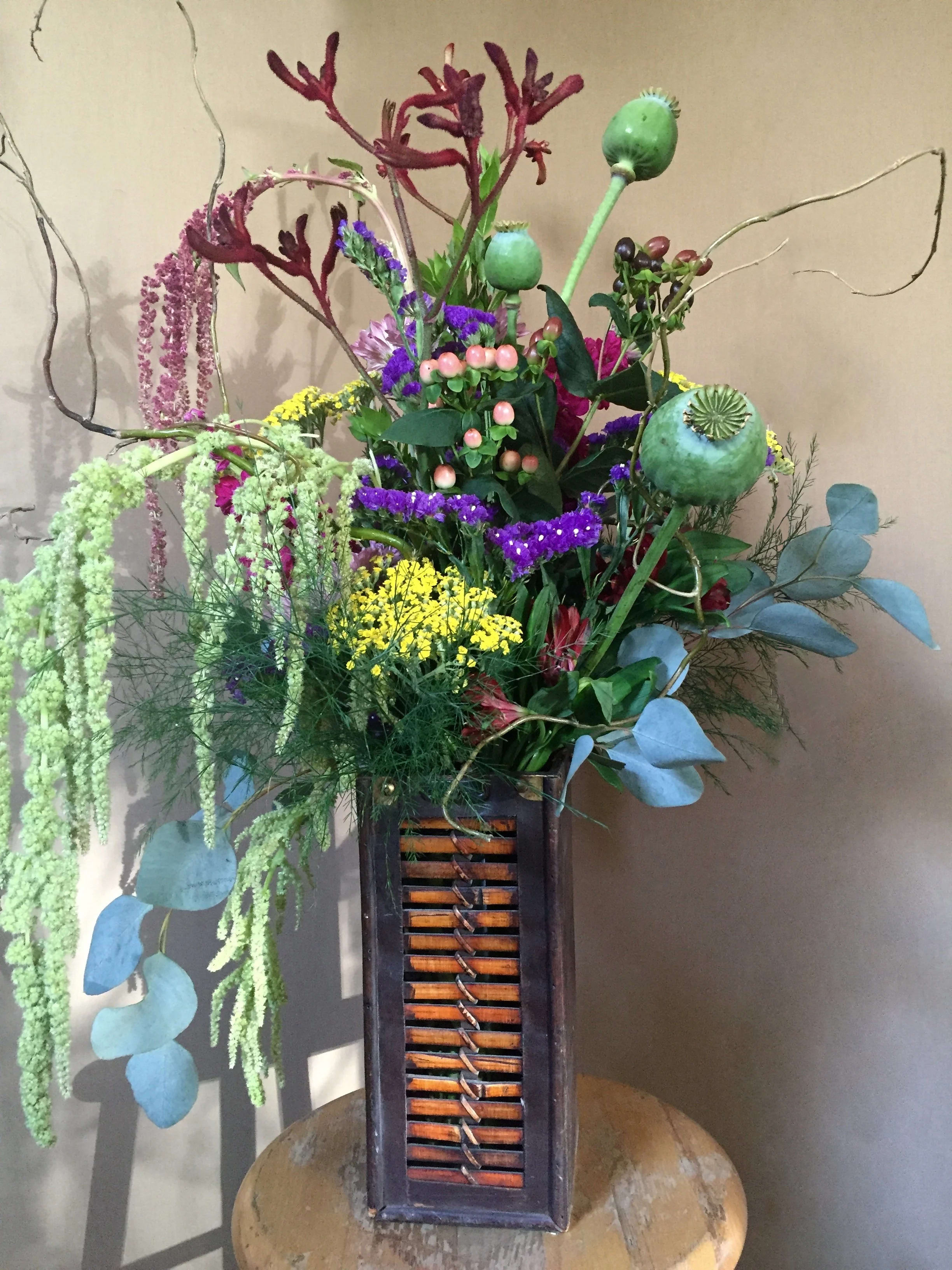 English Garden 001 - This unique design features green and red Hanging Amaranthus, Hypericums, papaver (somniferum), solidago, with tuch of lavender statice in a wooden wine box. Popular for center pieces or decor.(Floral/flower Color, vase may vary due to season and availability.)