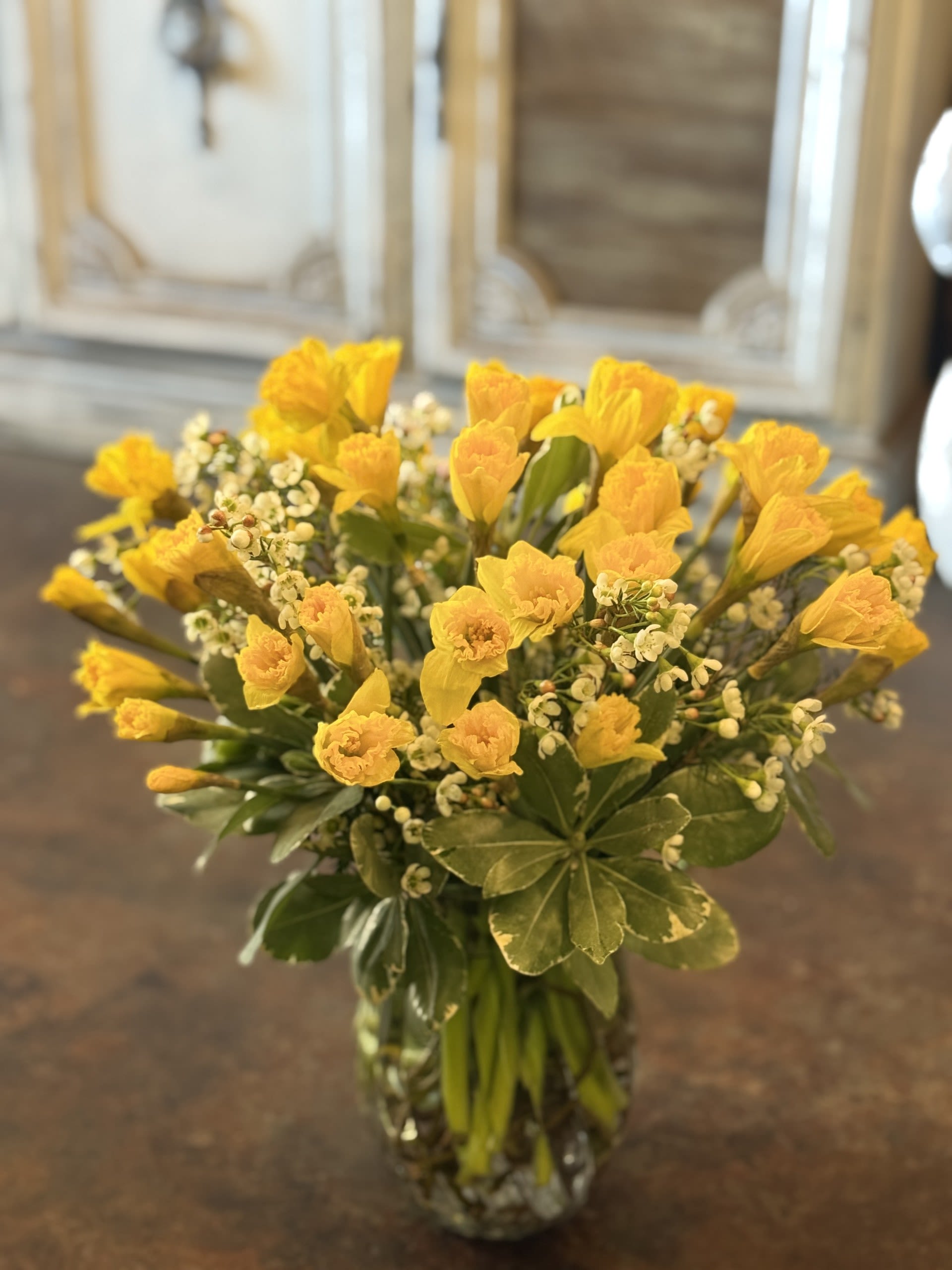 Golden Spring Glow  - A joyful burst of golden daffodils white blooms and fresh greenery, artfully arranged to bring brightness, positivity  and effortless seasonal beauty to every celebration. 
