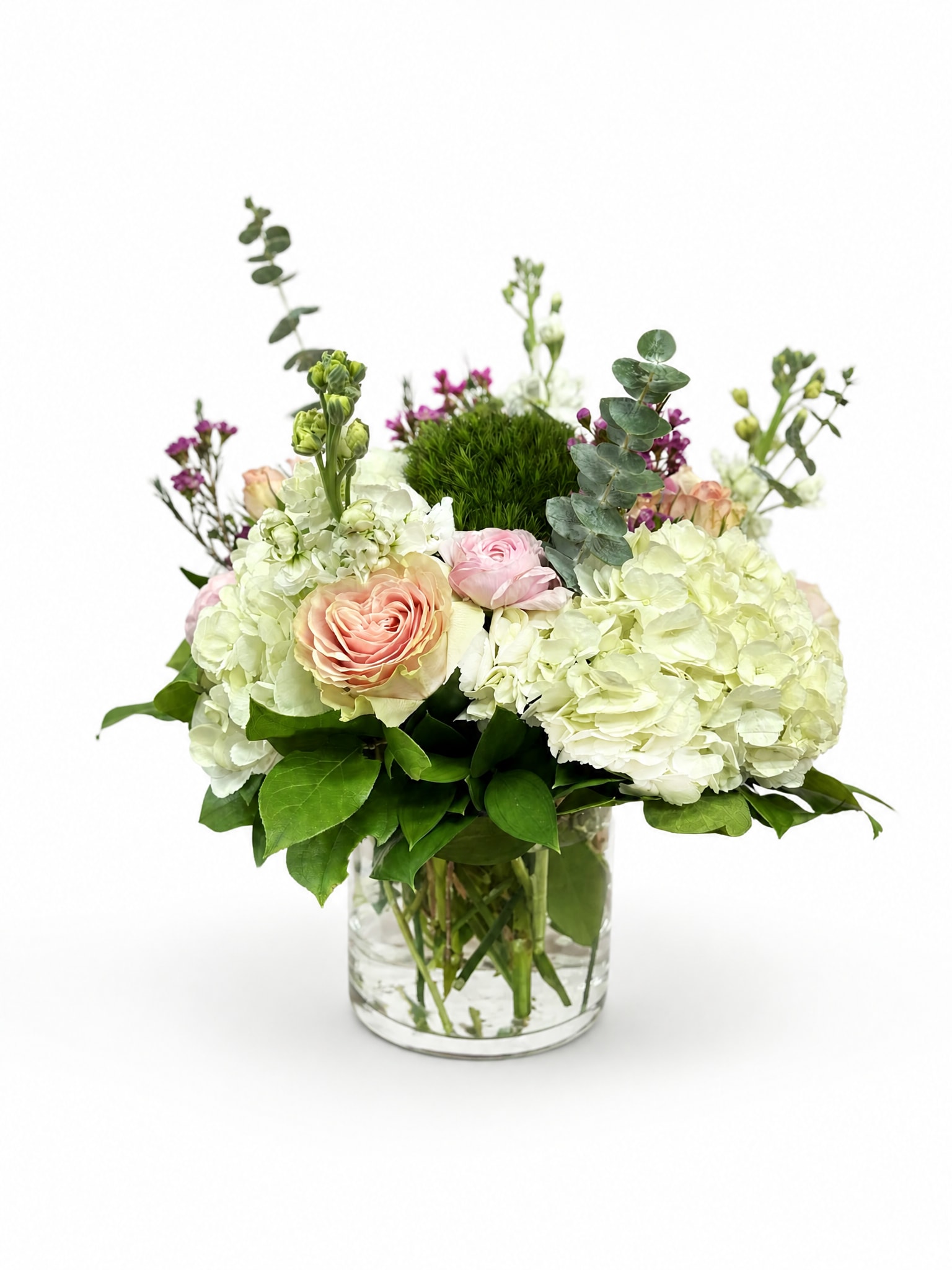 White hydrangeas and blush roses in a clear glass vase